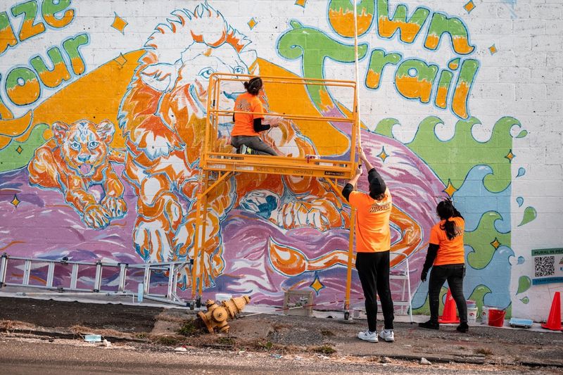 Blaze Your Own Trail mural by artist Alissa Siegal. Collaborators work on the mural featuring the words "Blaze Your Own Trail" with the image of lions and waves surrounding.
