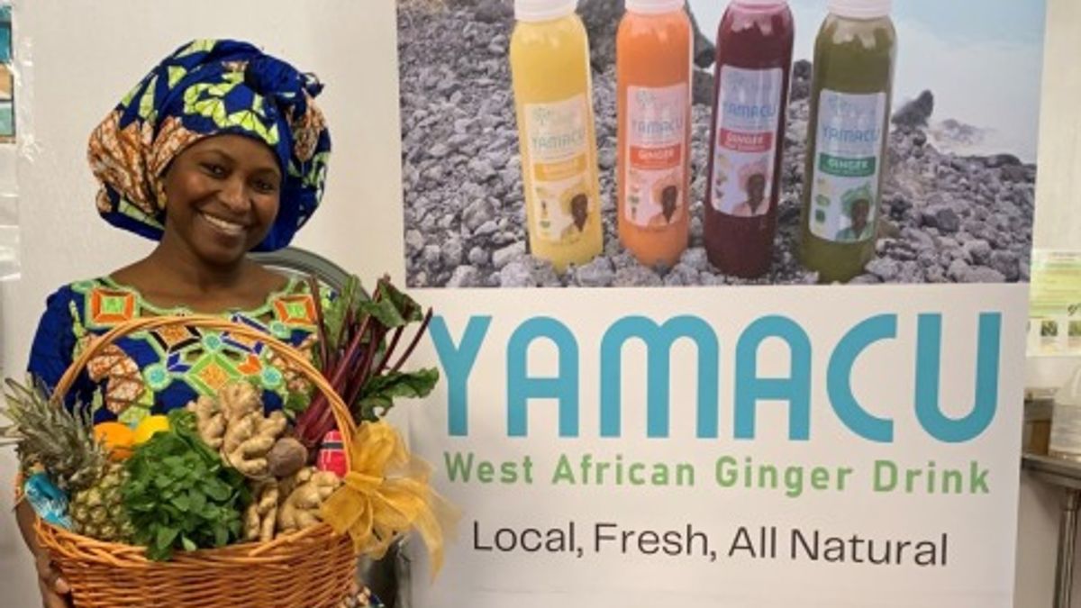 Salimata Bangoura, the founder of Yamacu, stands in front of a stand-up banner for her business. 