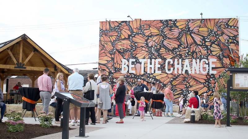 The grand opening of Monarch Commons featuring a mural that states “BE THE CHANGE” over a background of Monarch wings.