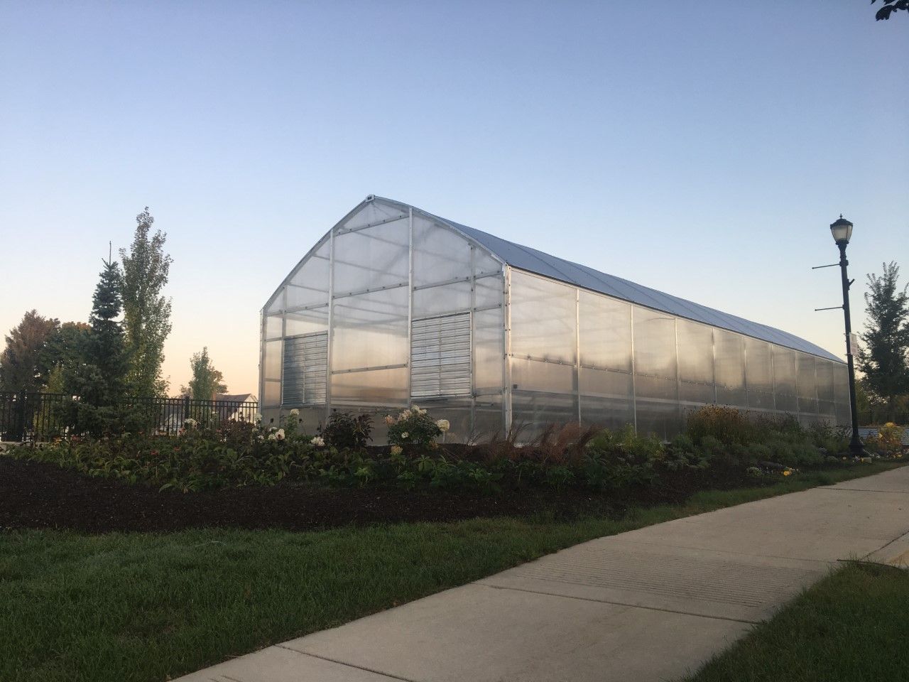 The greenhouse surrounded by landscaping and flowers.