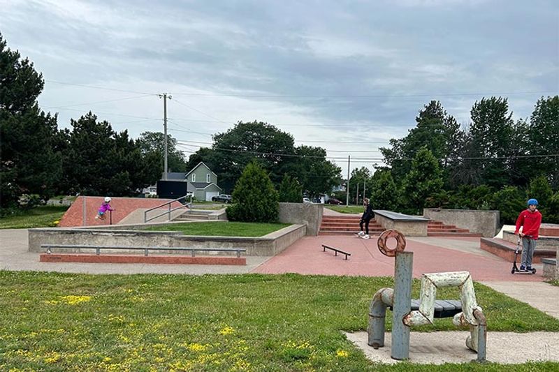 One child and two teens skate and scooter around the features at the concrete Marquette Skatepark.