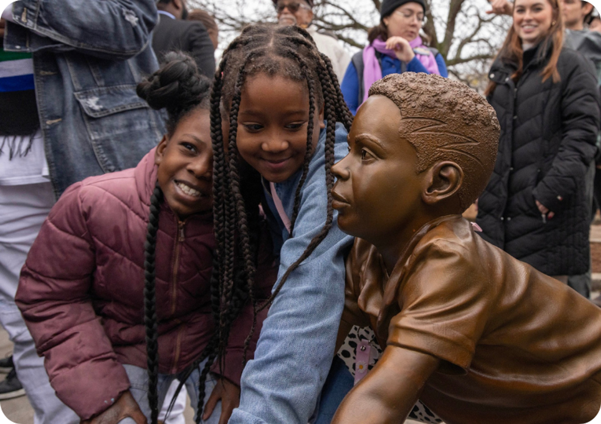Two young girls pose by the sculpture of the boy at the Unified Civic Monument