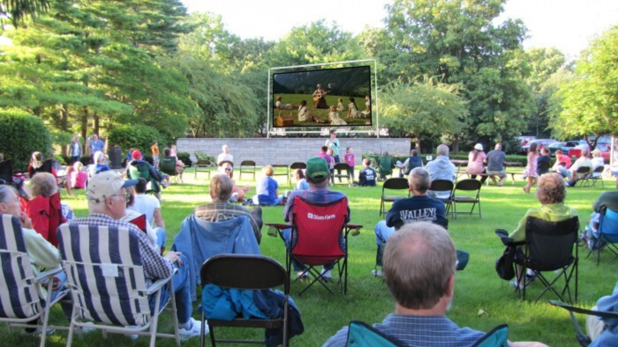 Community members sit in chairs on a grassy park lawn during Tecumseh Movies in the Park.