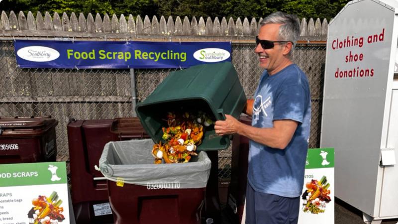 A man pours food scraps into a community food scrap recycling bin.