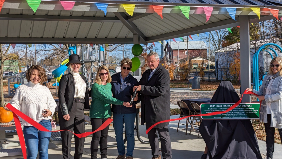 A group of people happily cut the ribbon during a project grand opening. 