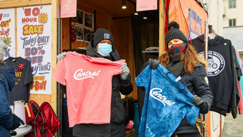 Two women hold up t-shirts from a local market stall