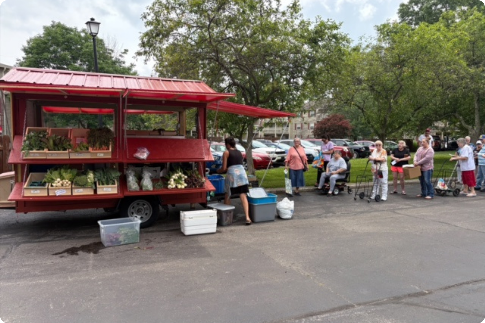 Elderly customers queue up at the Farm Stand in a parking lot.