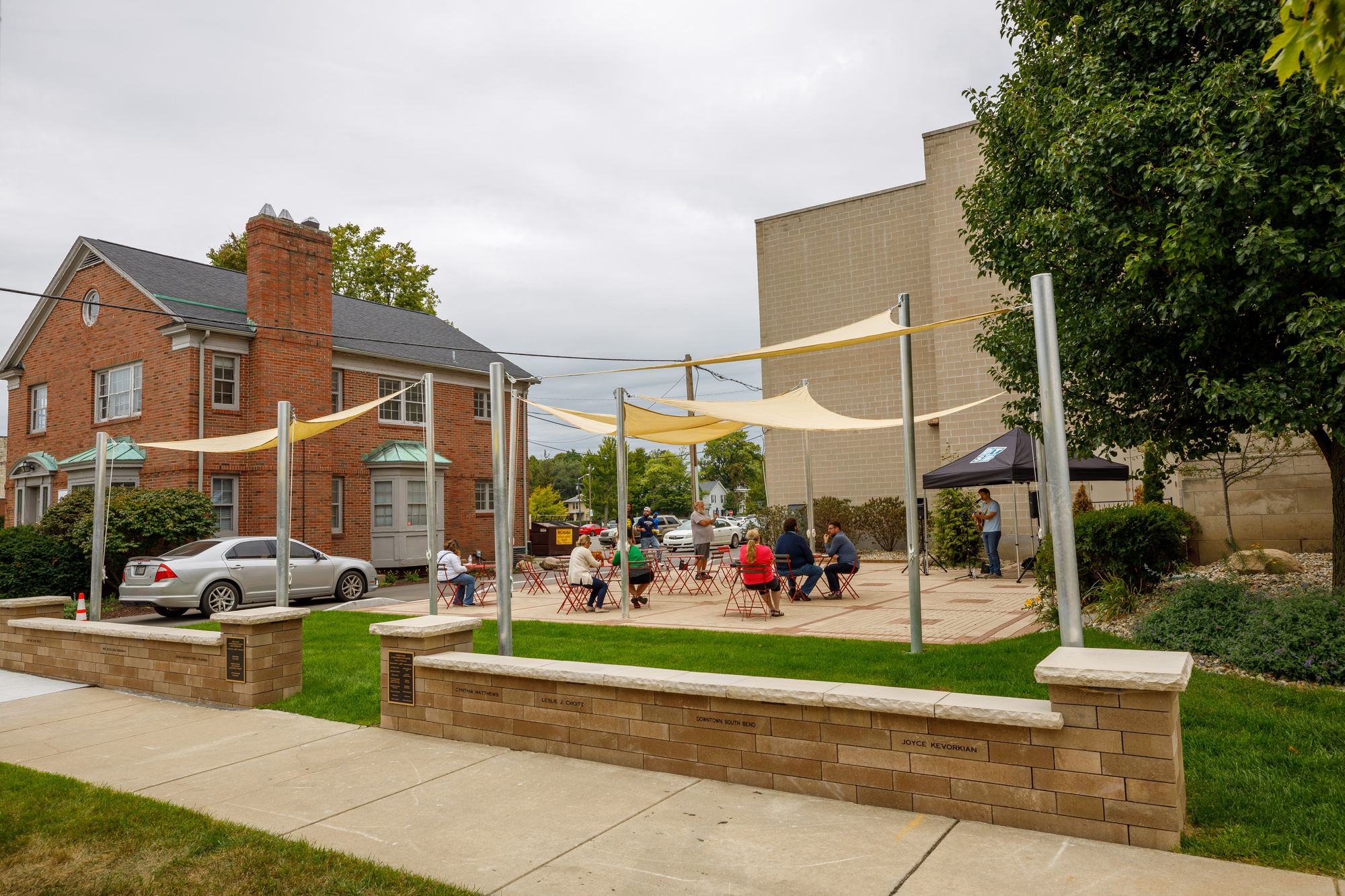 Foegley Plaza features sunshades above tables and chairs for community members outdooring a live performance. 