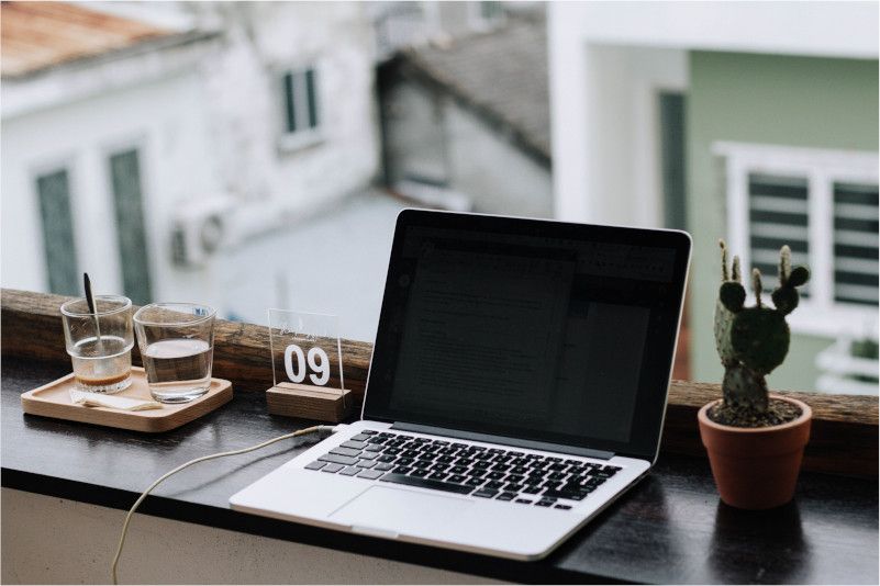A macbook over the window with two glasses and a cactus plant. Photo by Nguyen Dang Hoang Nhu on Unsplash