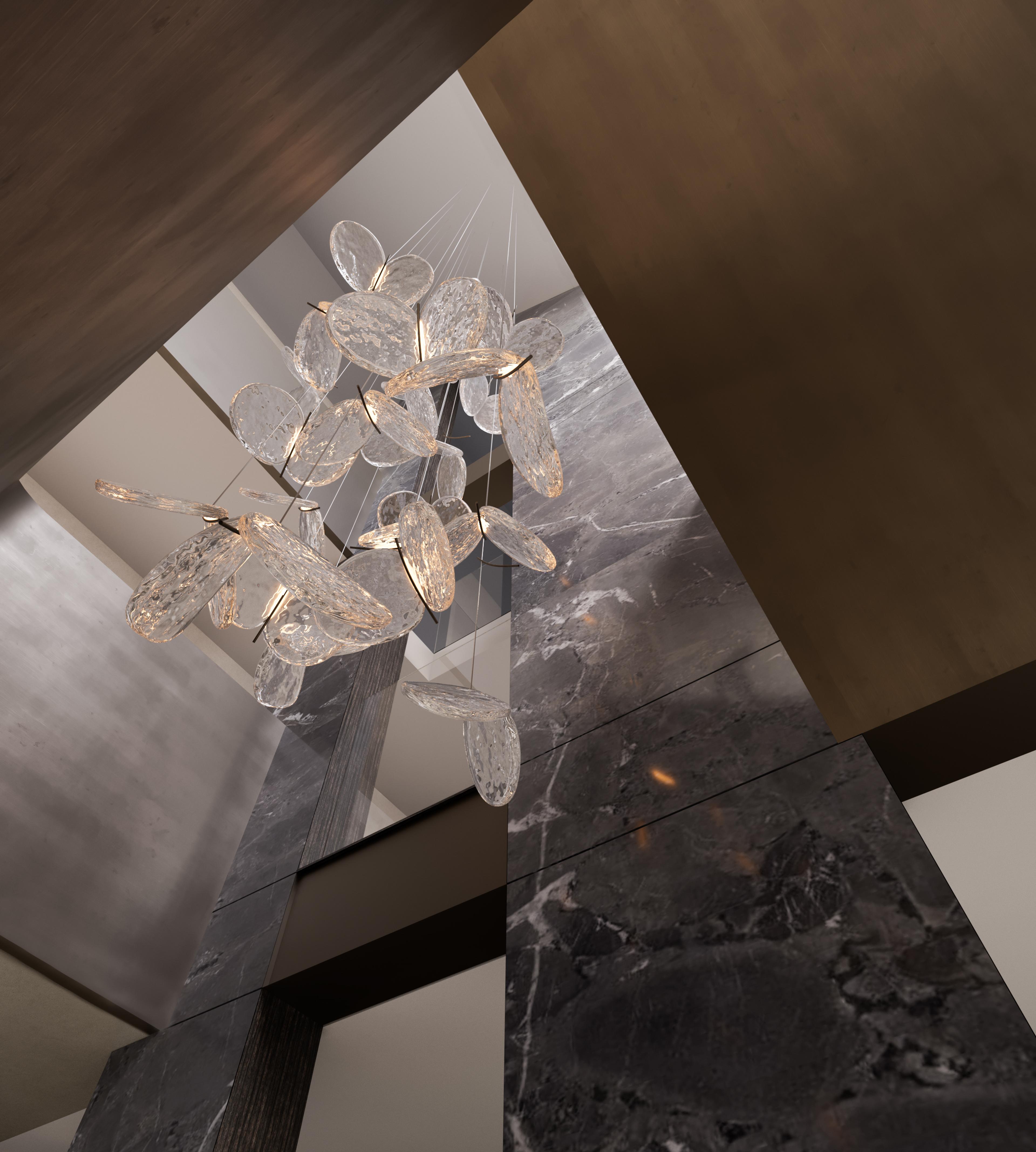 View up into a stairwell with a cluster of glass disc pendant lights and dark marble columns