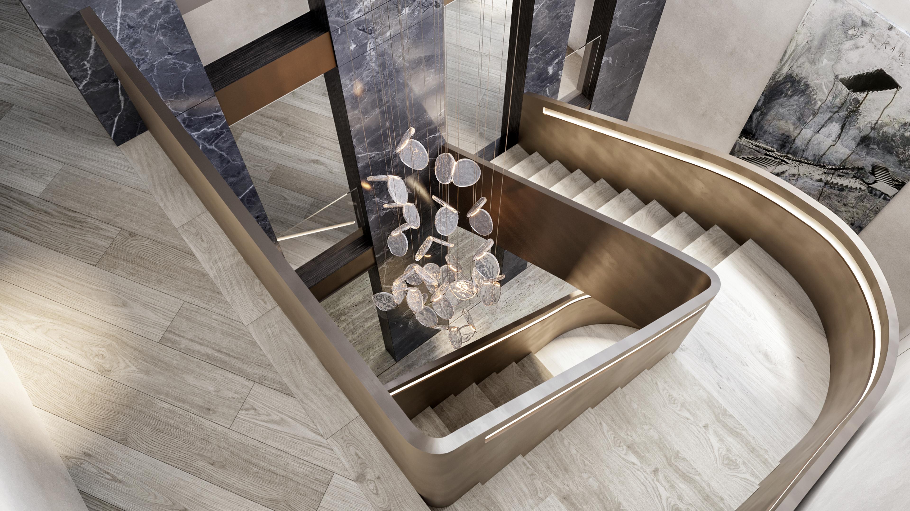 Top-down view of the curved bronze staircase with a glass disc chandelier