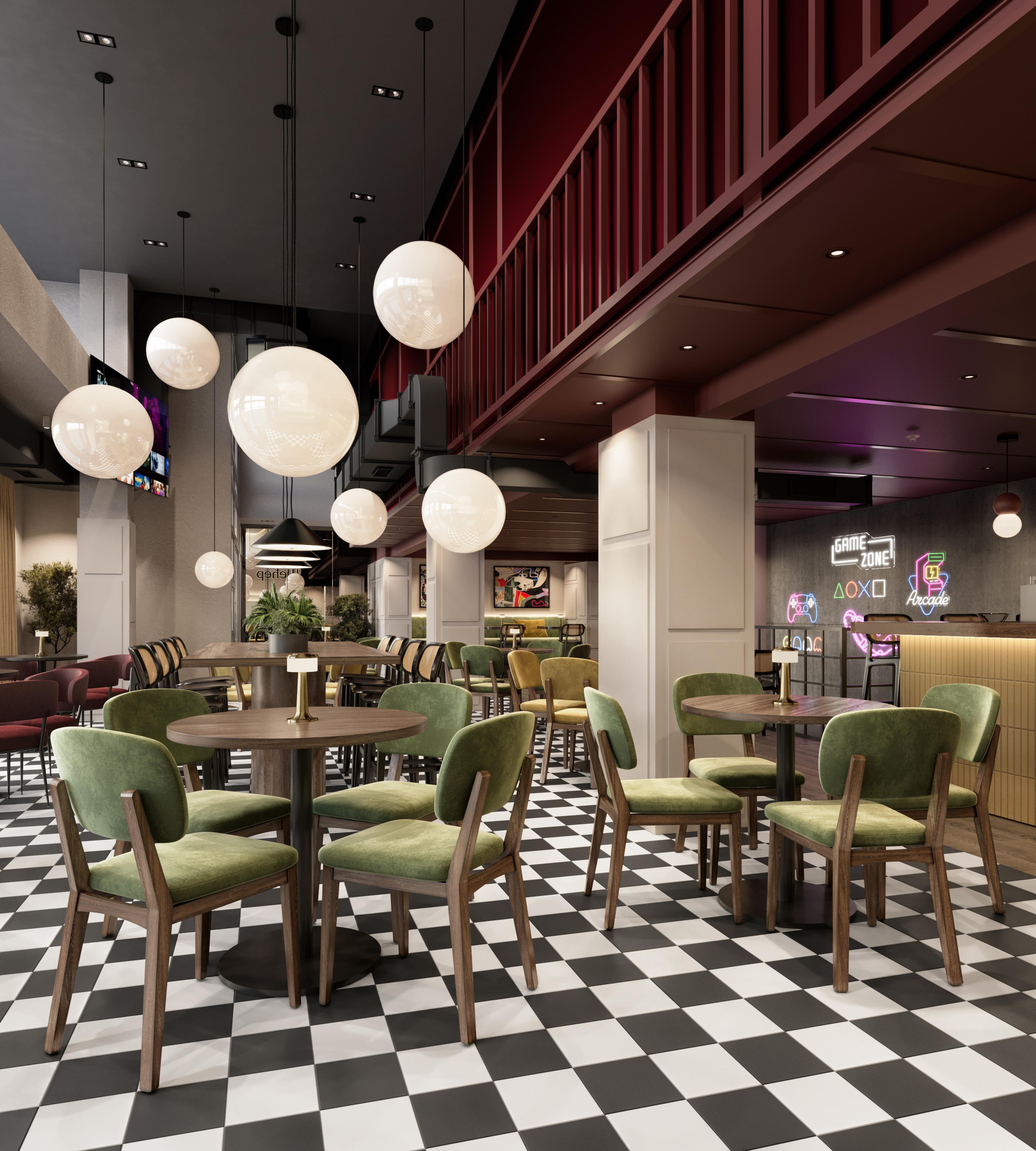 Cafe seating under a burgundy mezzanine with round tables and green chairs
