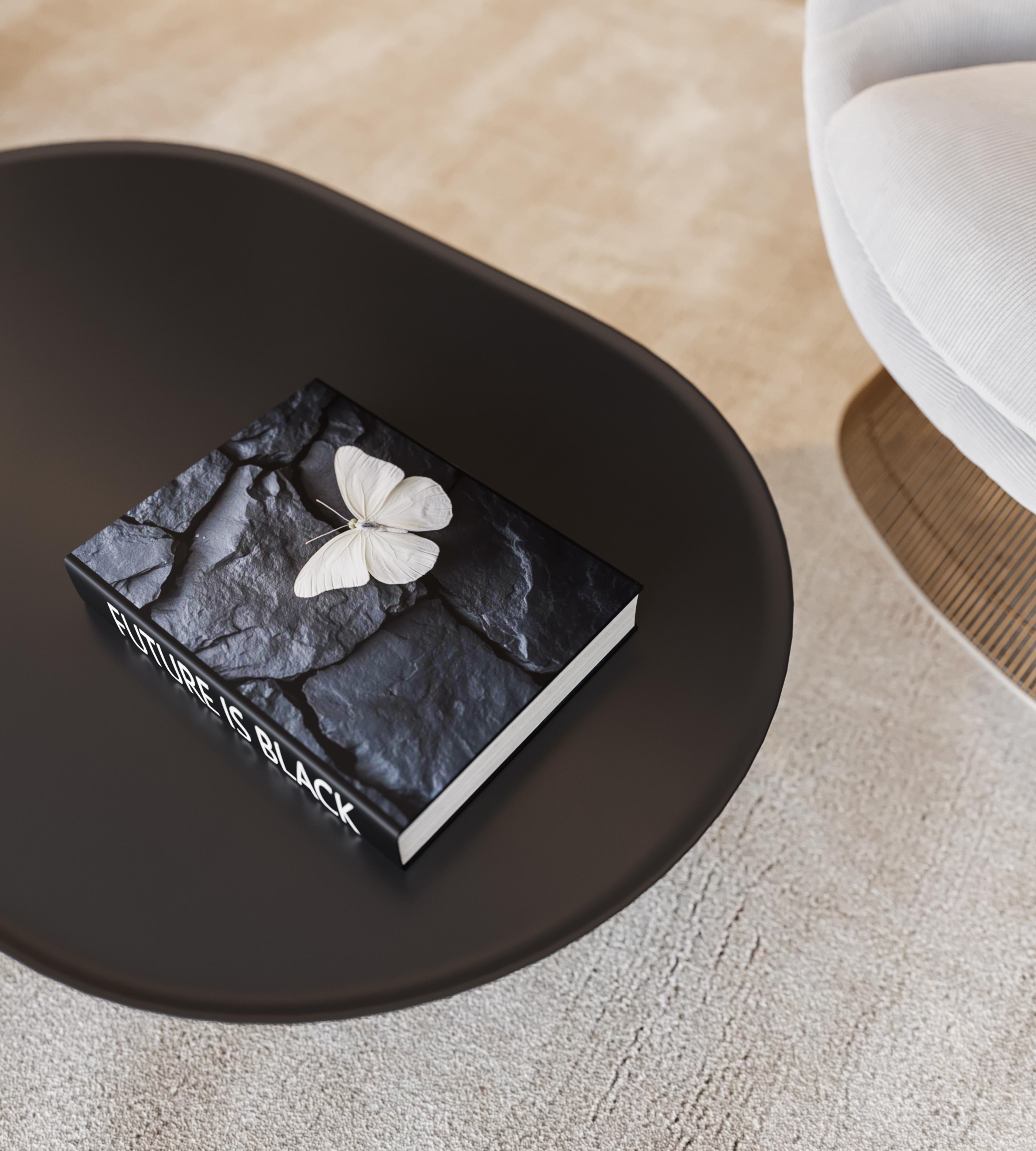 Close-up of a black coffee table with a black stone-textured book and a white butterfly