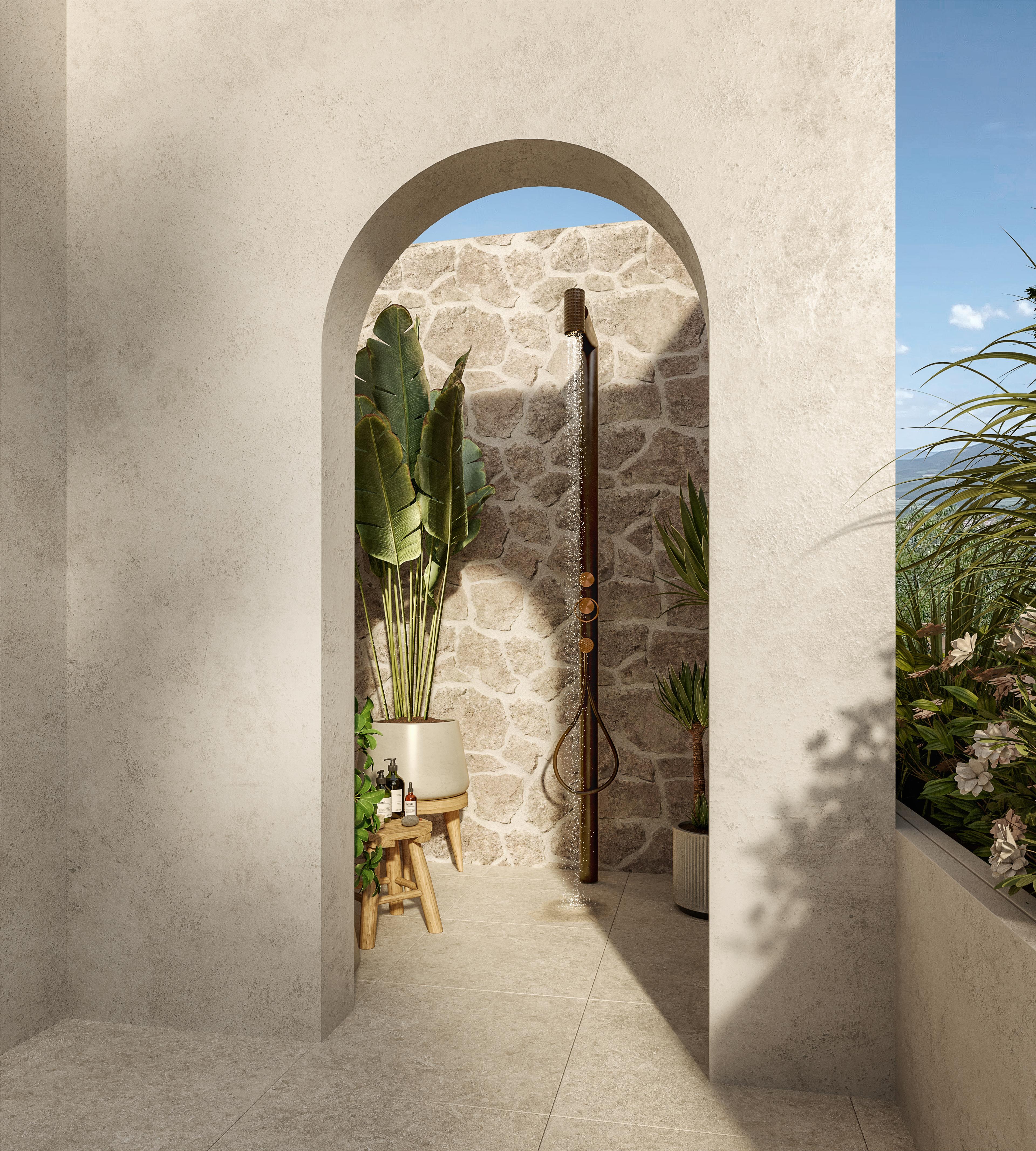 Outdoor shower in a stone-lined arch with tropical plants