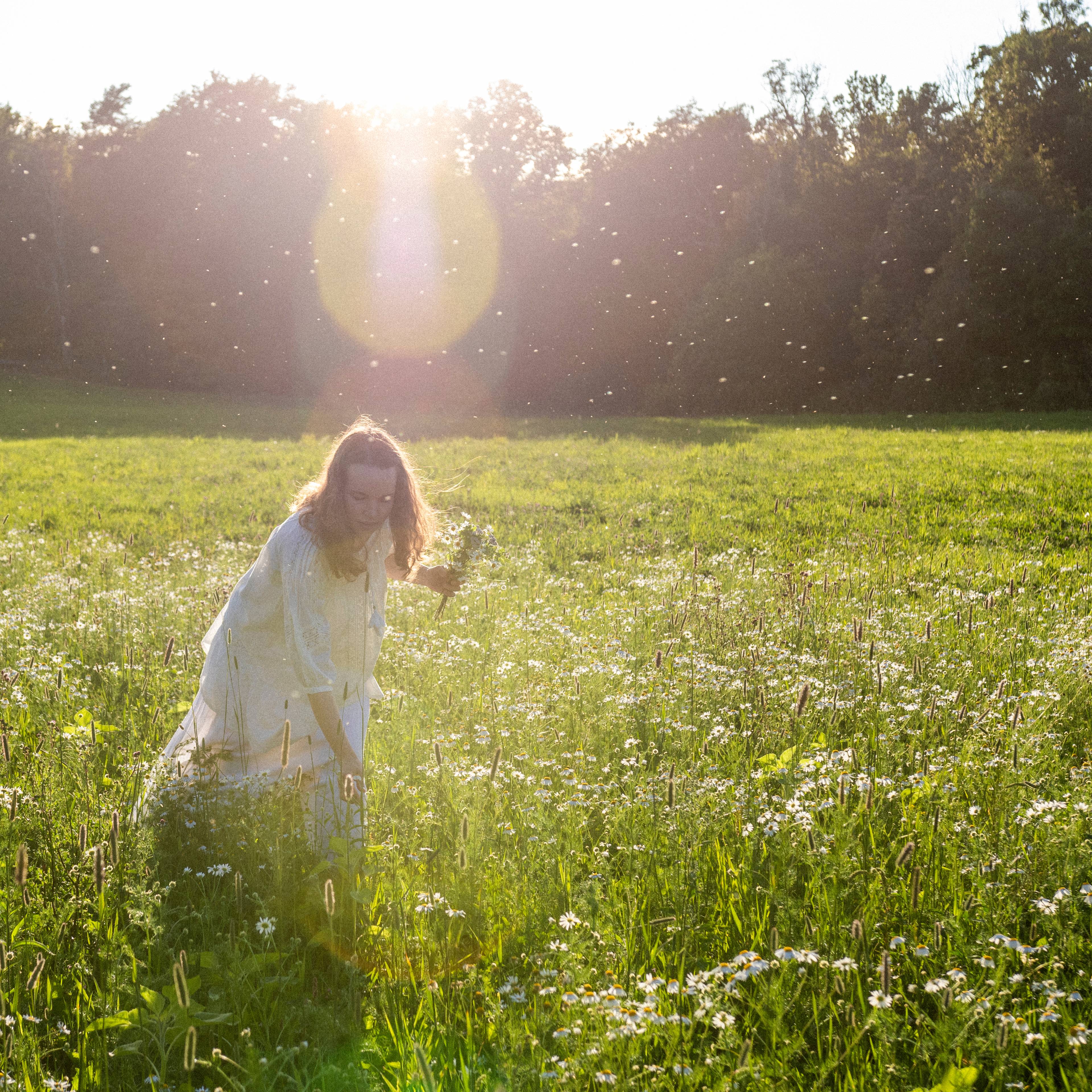 A girl picking flowers in a field.