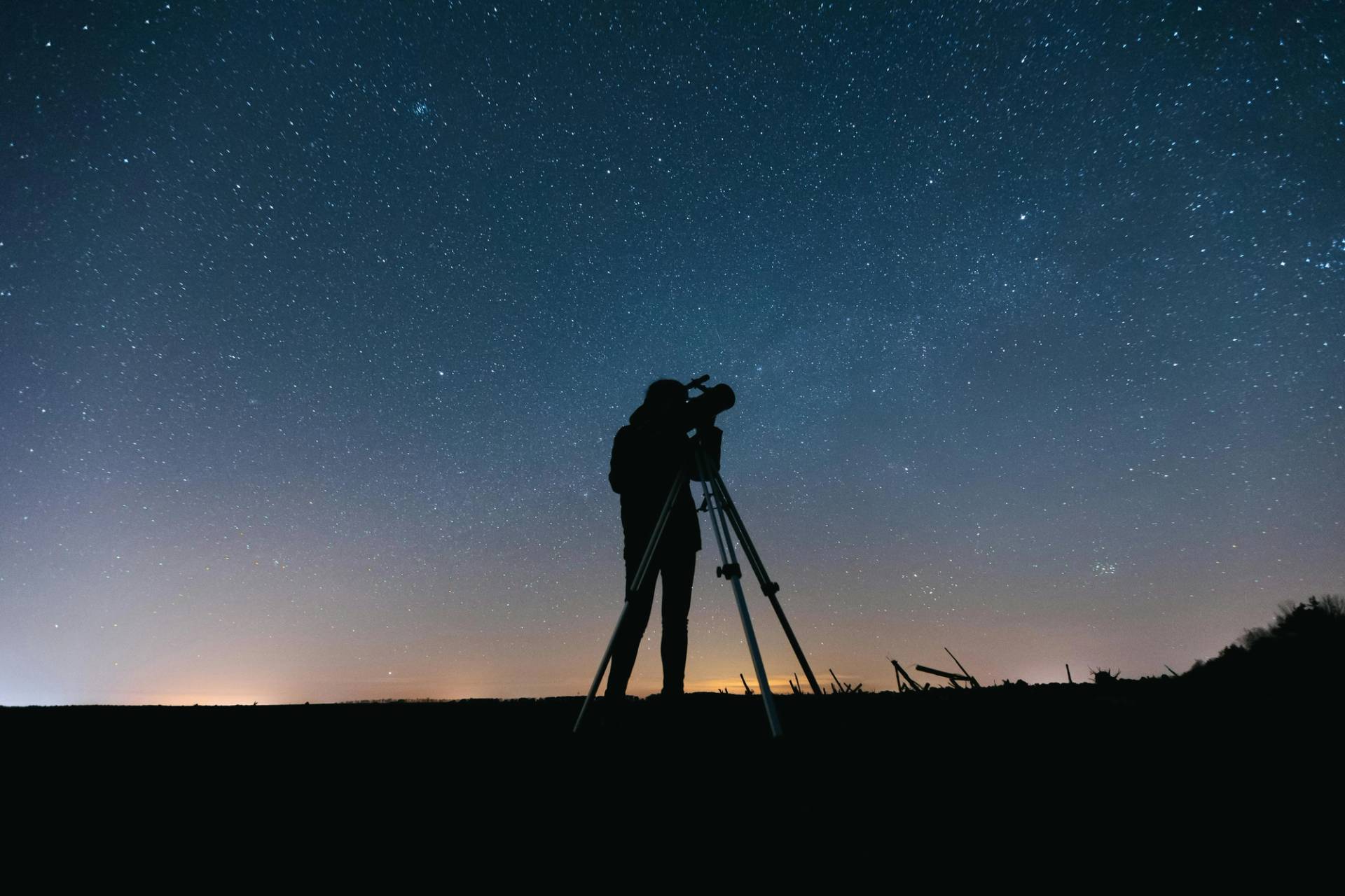 A man looking at the sky with a telescope.