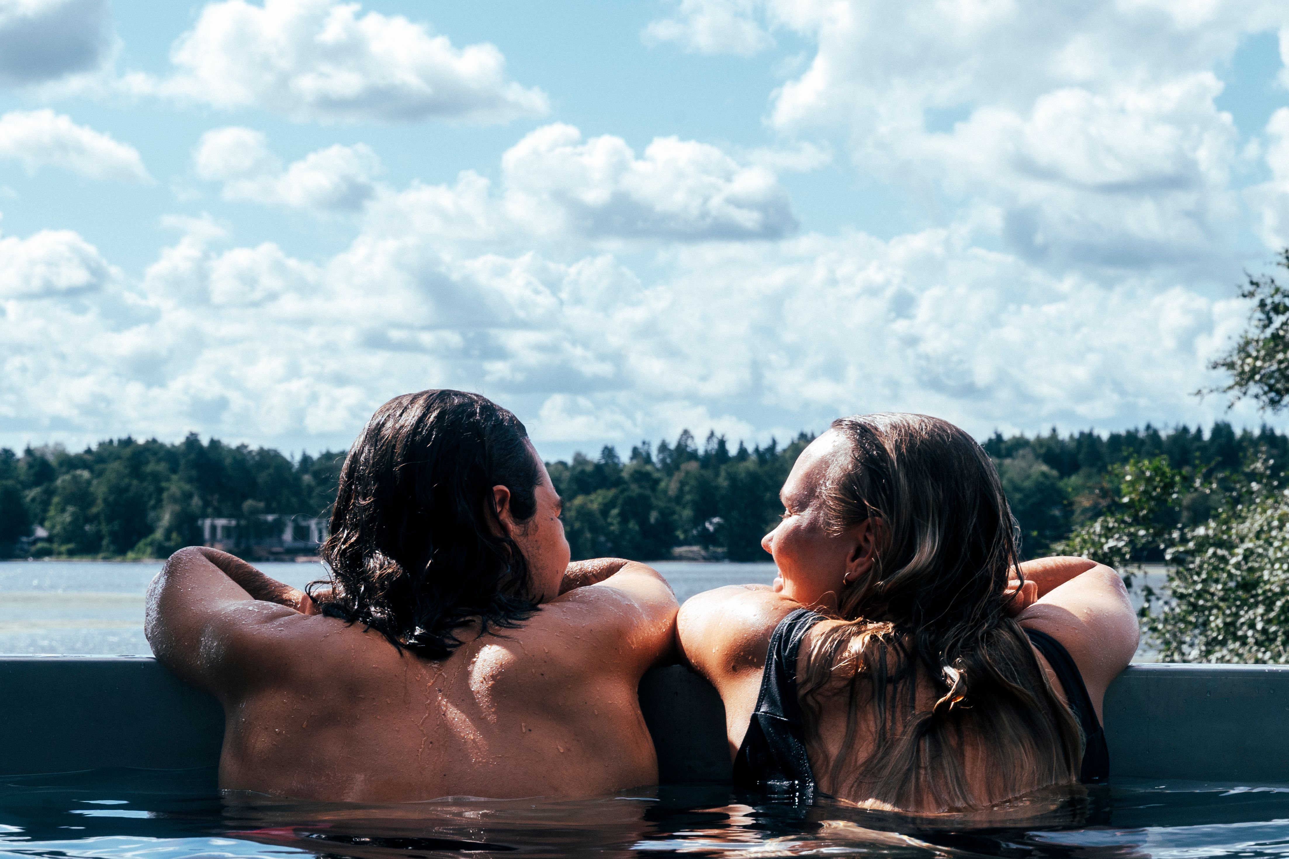 Two people enjoying a wood-fired hot tub.