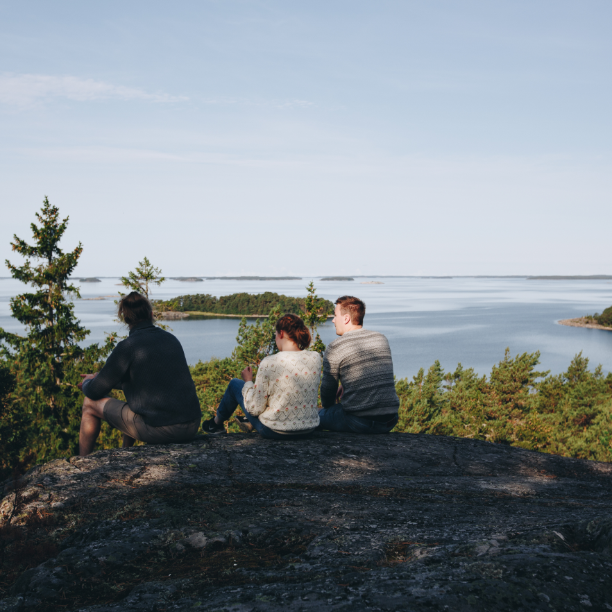 Three people sitting on rocky terrain.