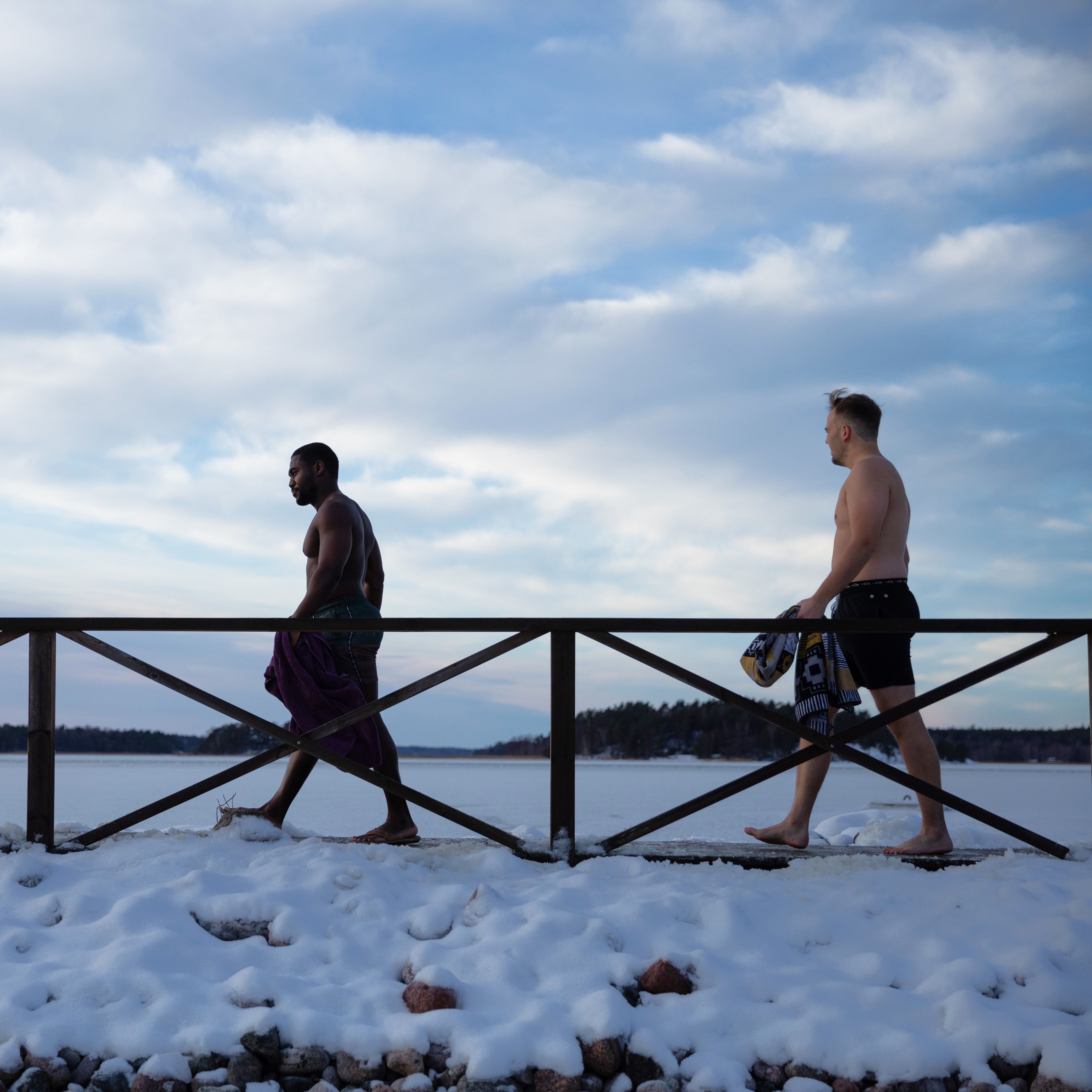 Two people walking on an icy dock towards the water.