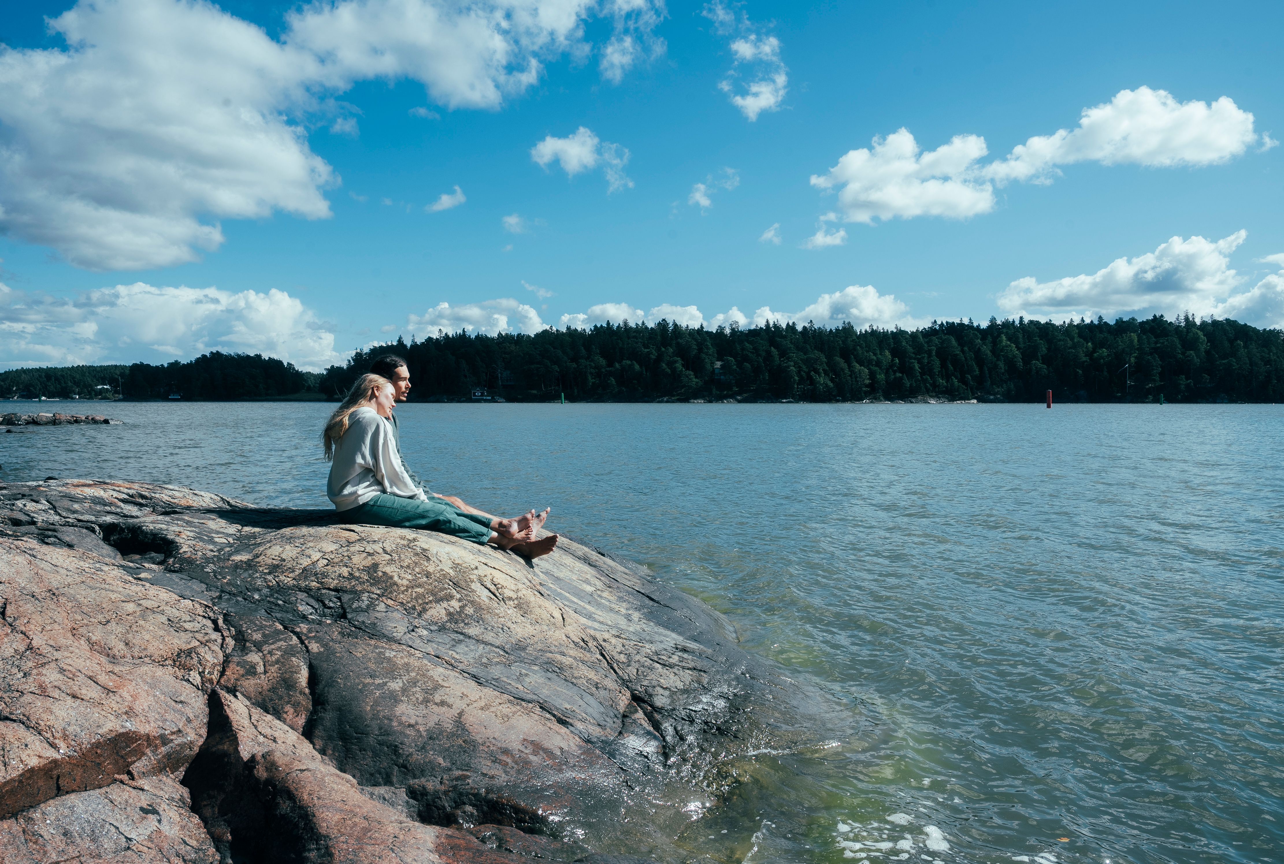Two people sitting on shore rocks.