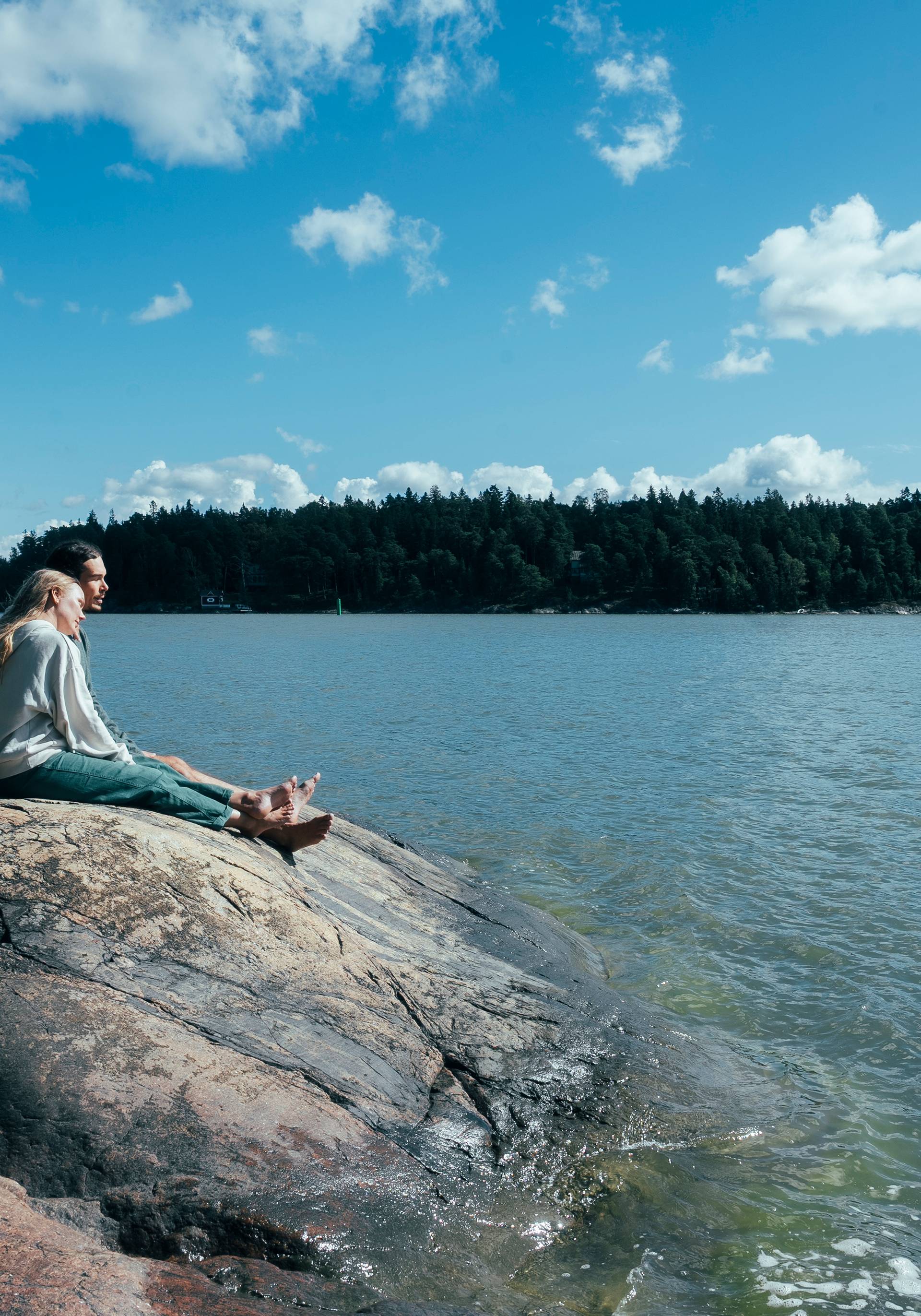 Two people sitting on shore rocks.