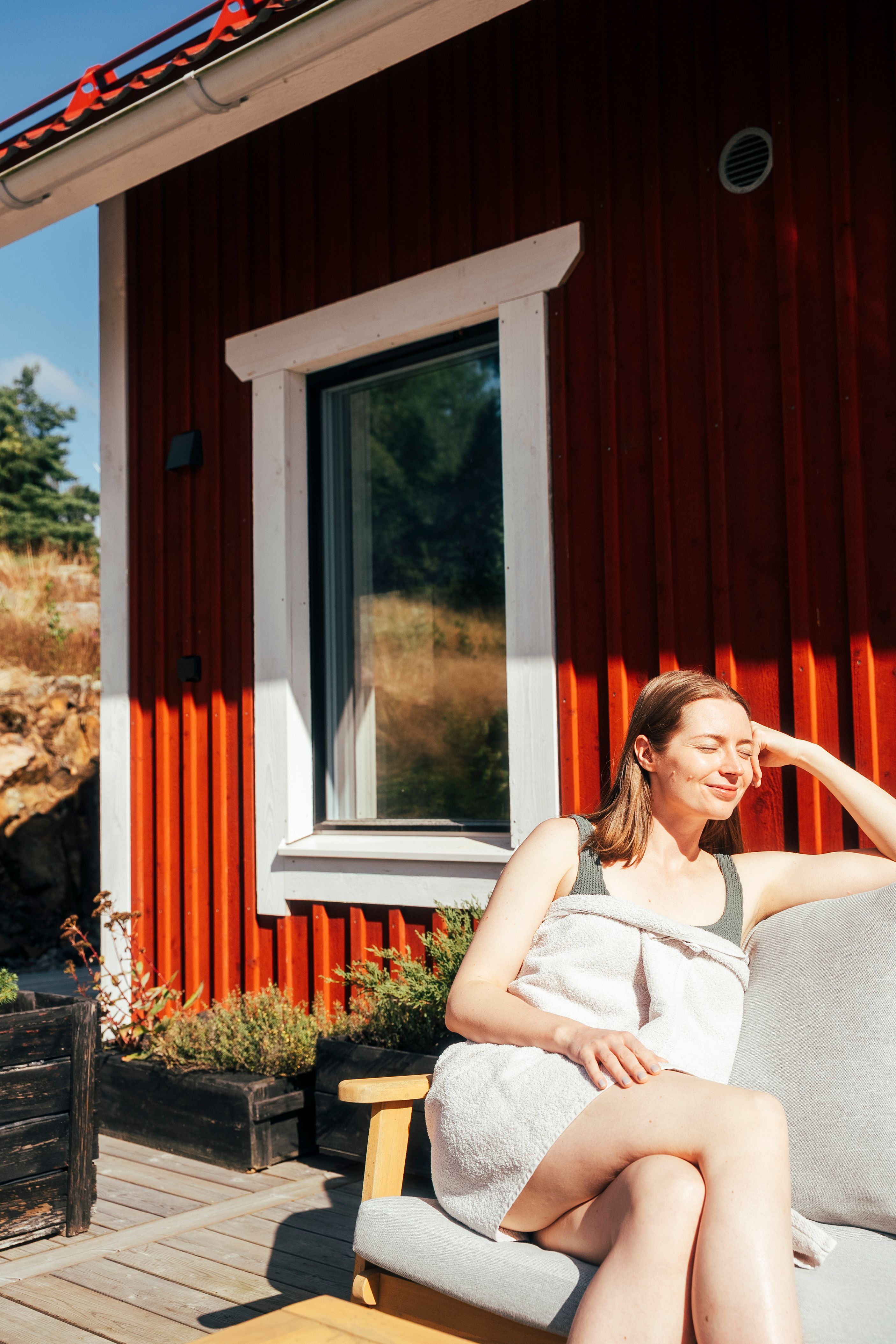 A woman enjoying the sun outside of a sauna.