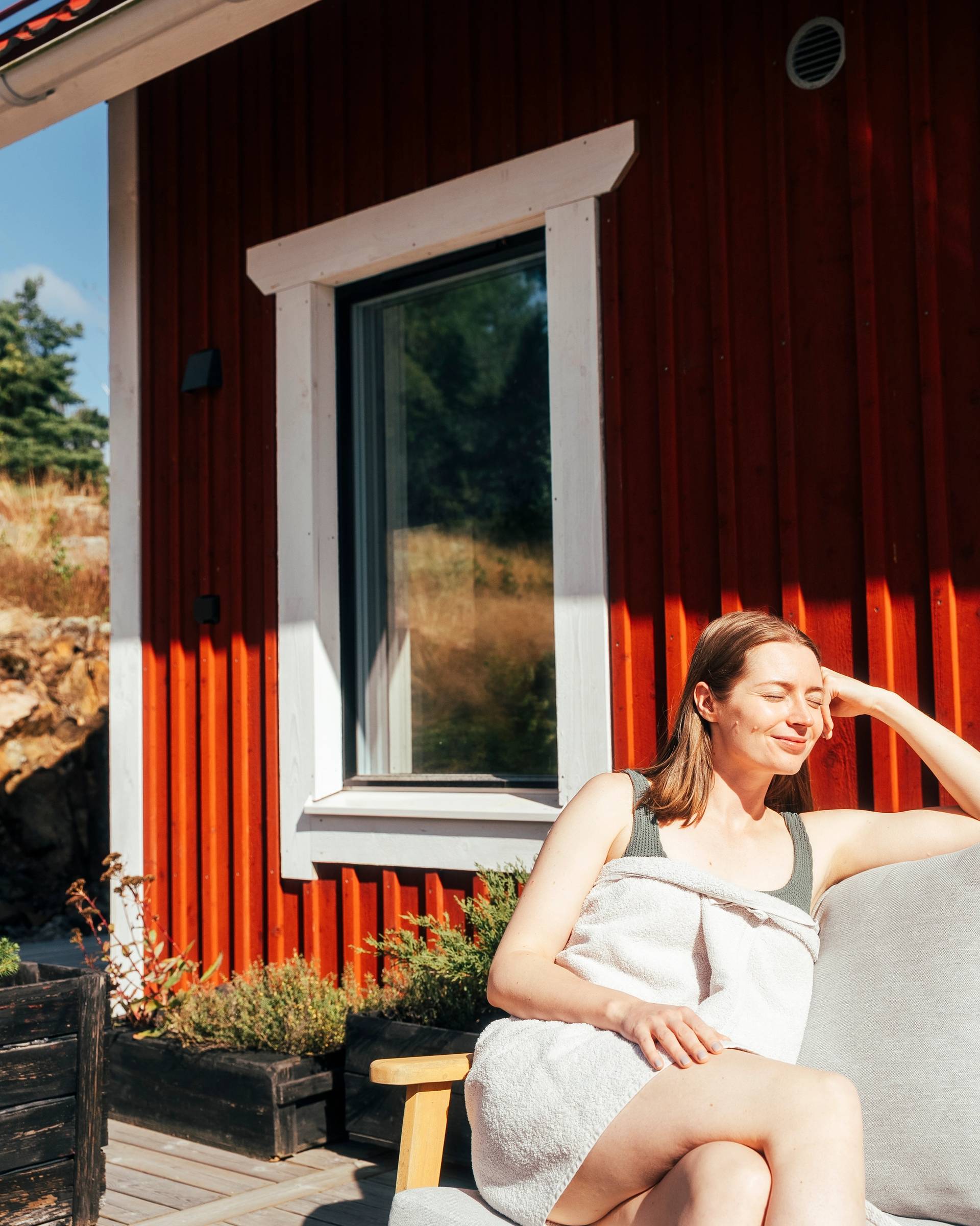 A woman enjoying the sun outside of a sauna.