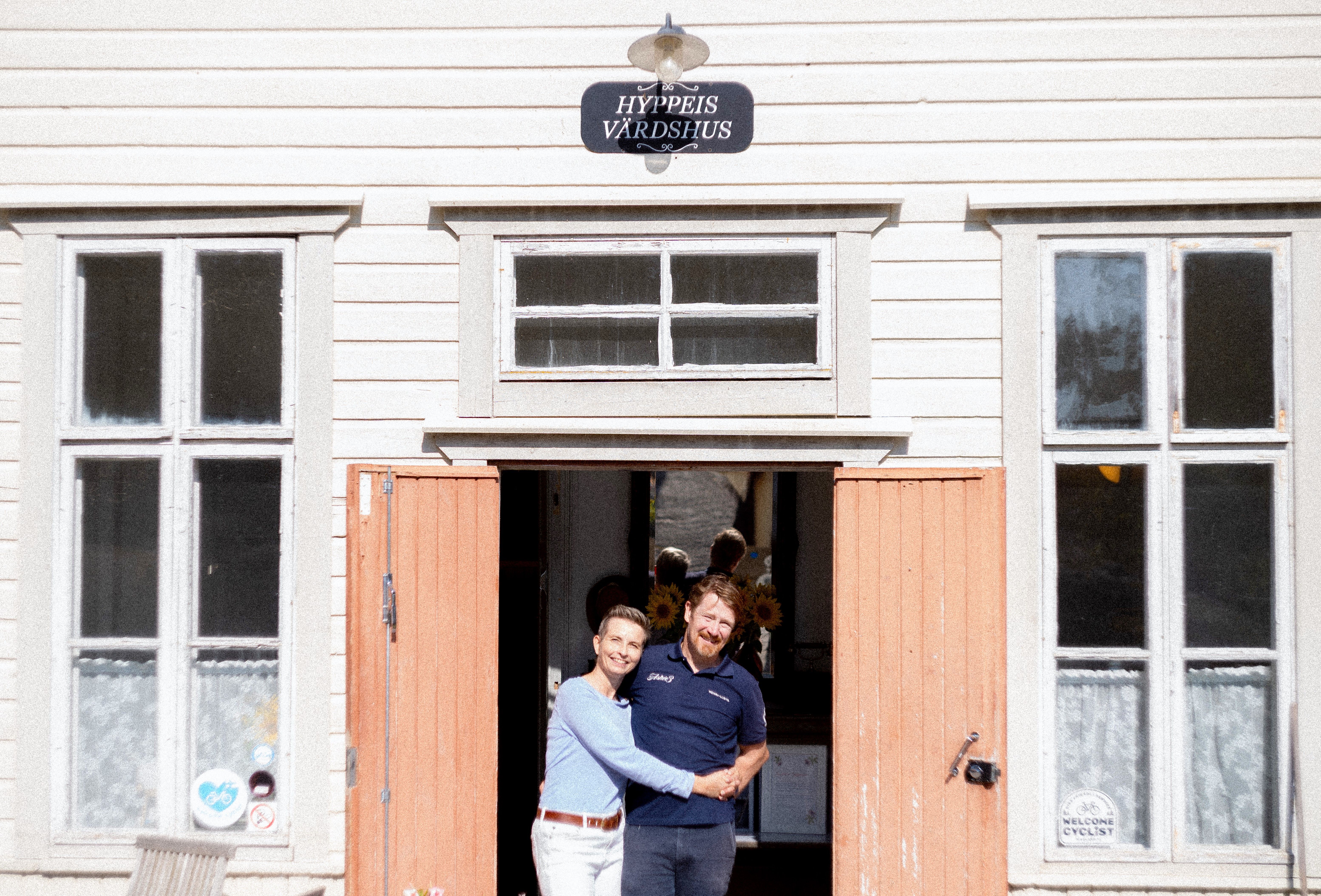 Hotel owners Outi and Sam hugging on the porch.