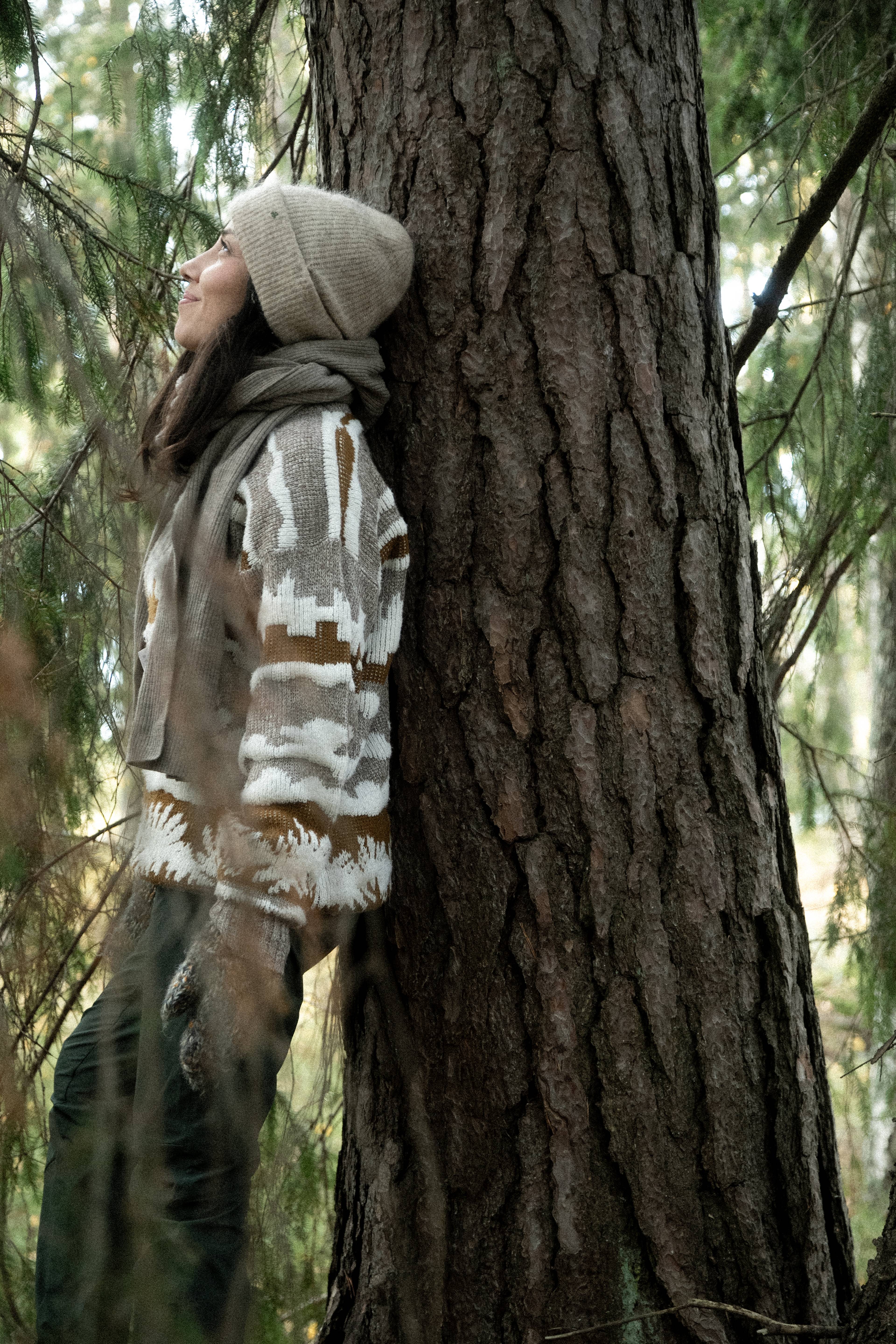 A woman leaning on a pine tree.