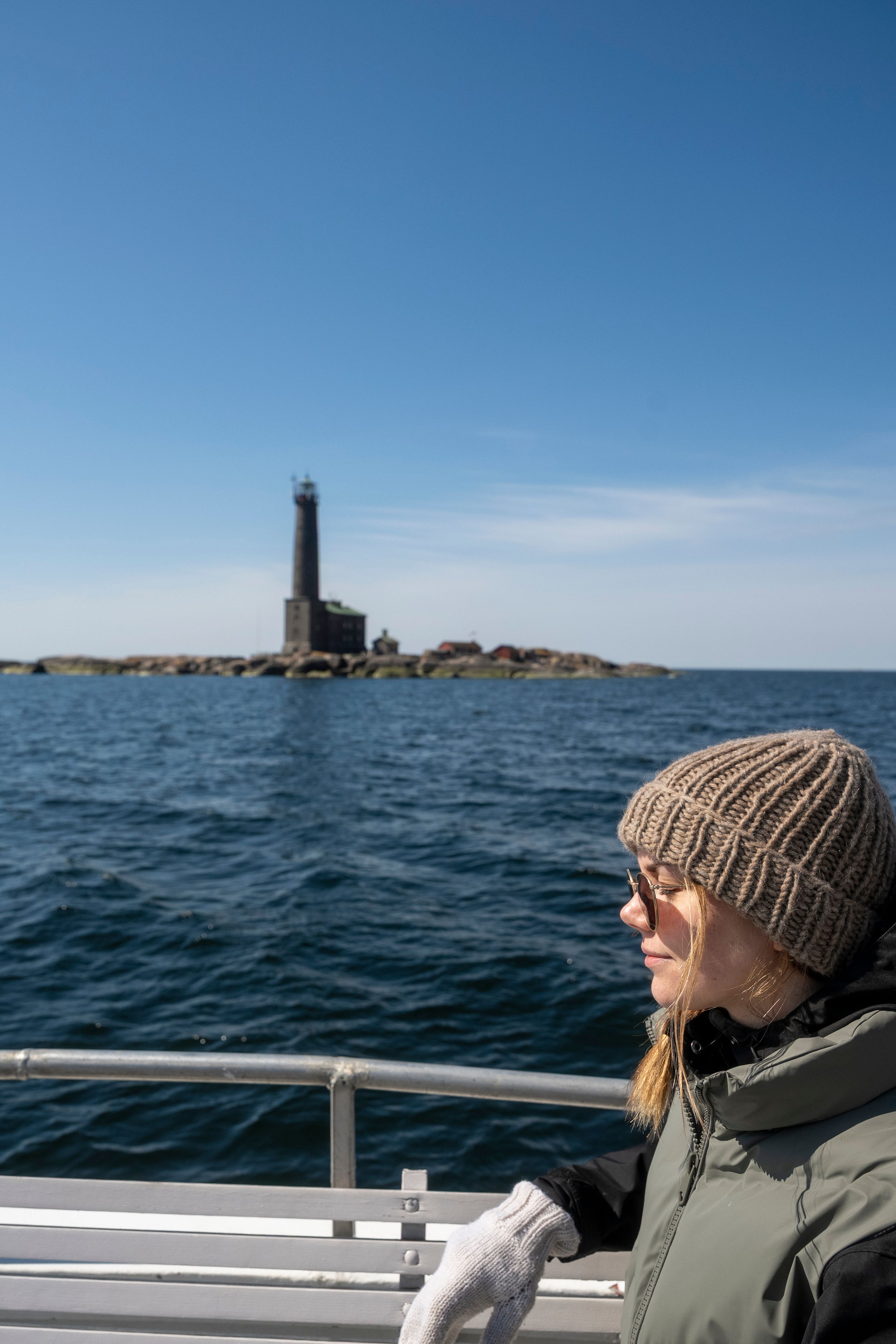 A girl on a boat with a lighthouse in the background.