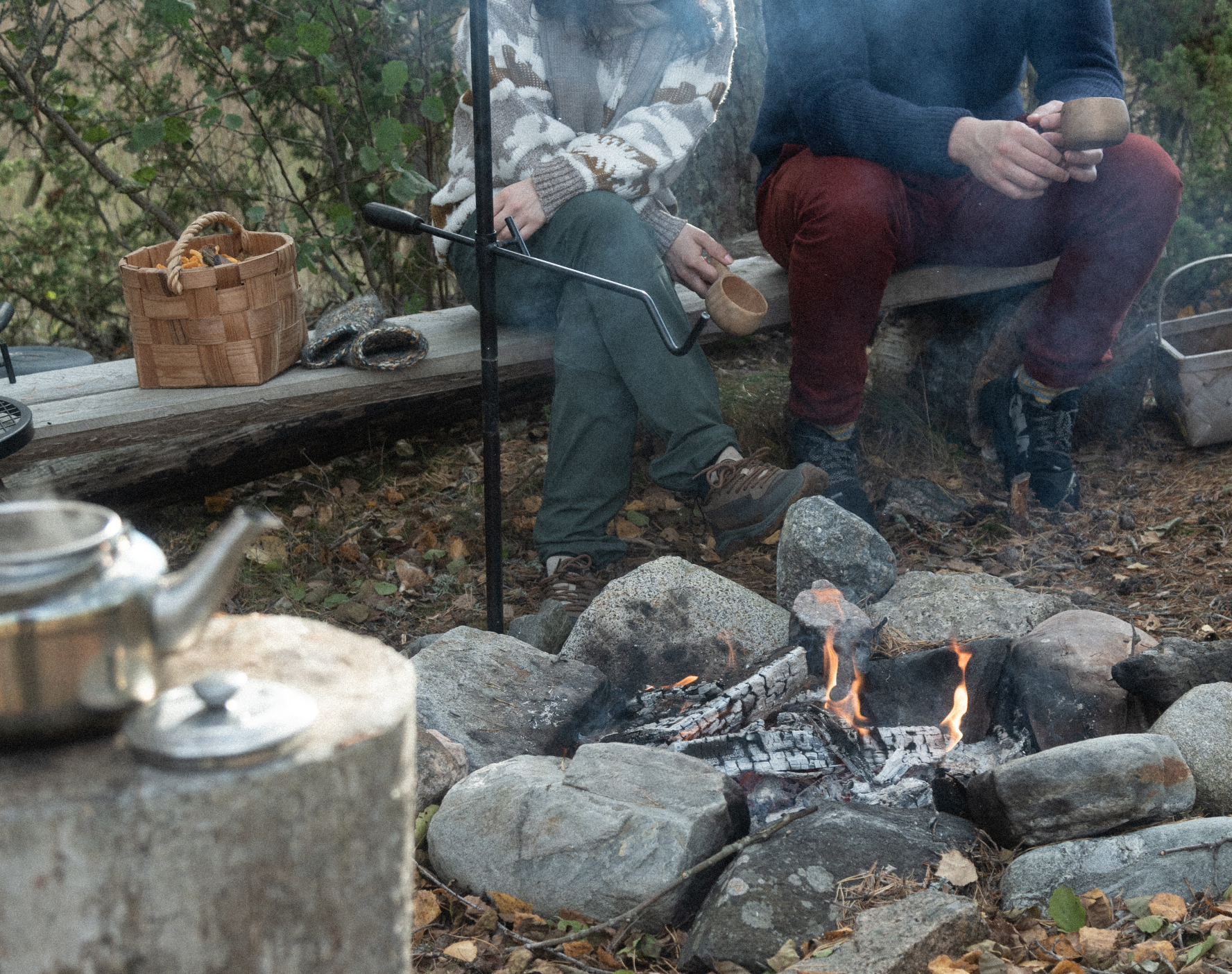 Two people sitting side-by-side near a camp fire