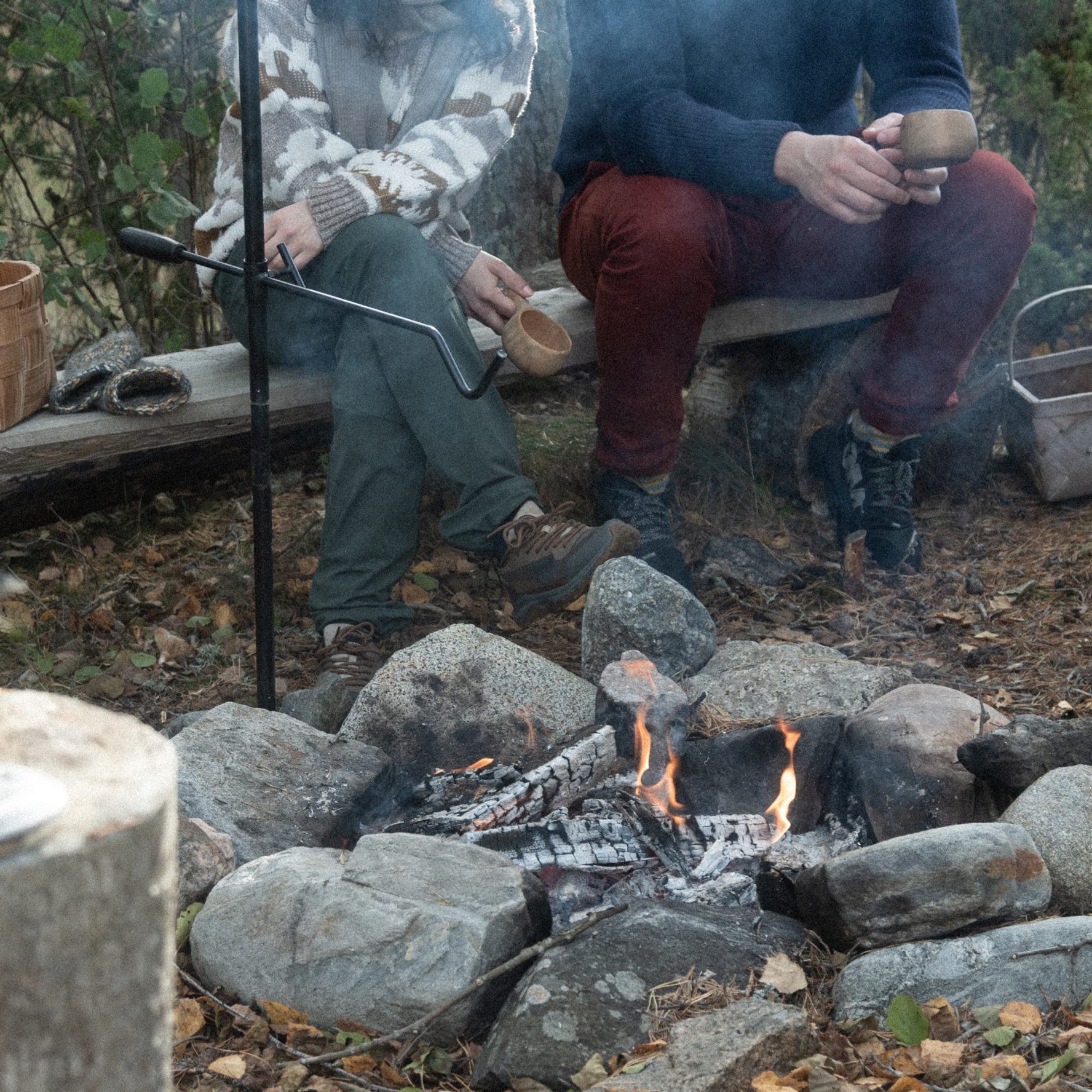 Two people sitting side-by-side near a camp fire