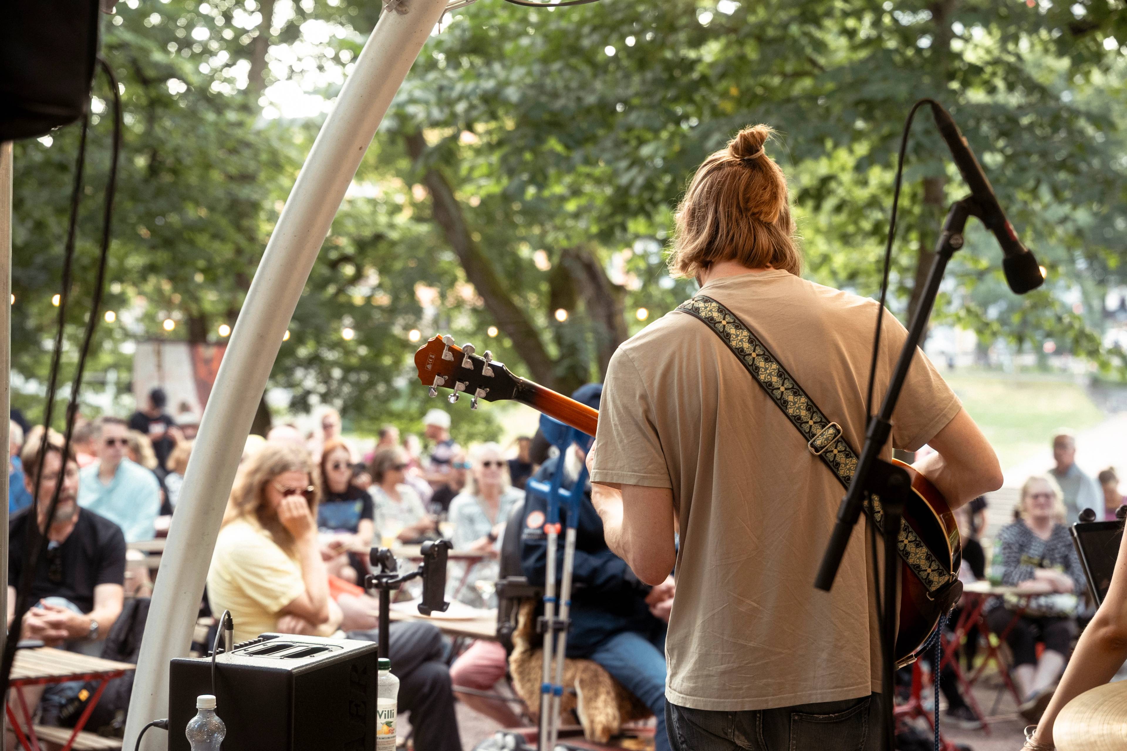 A person playing guitar in front of a crowd.