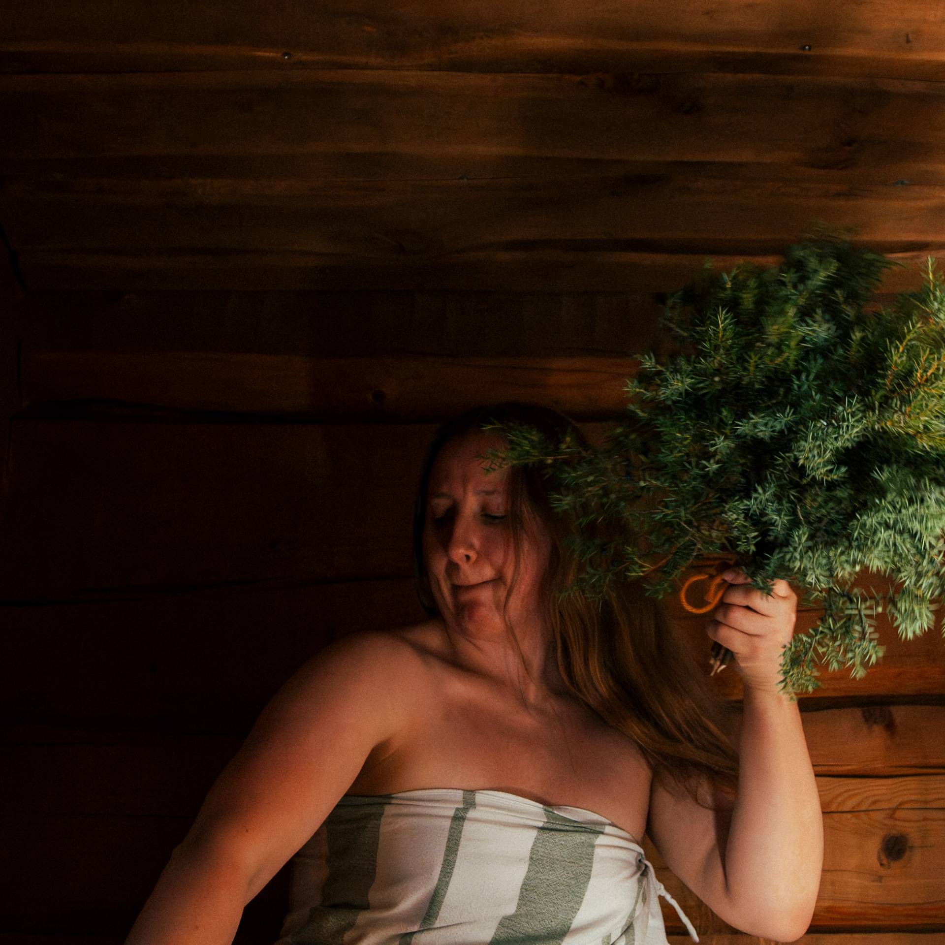 A woman whisking her skin with a tree branch.