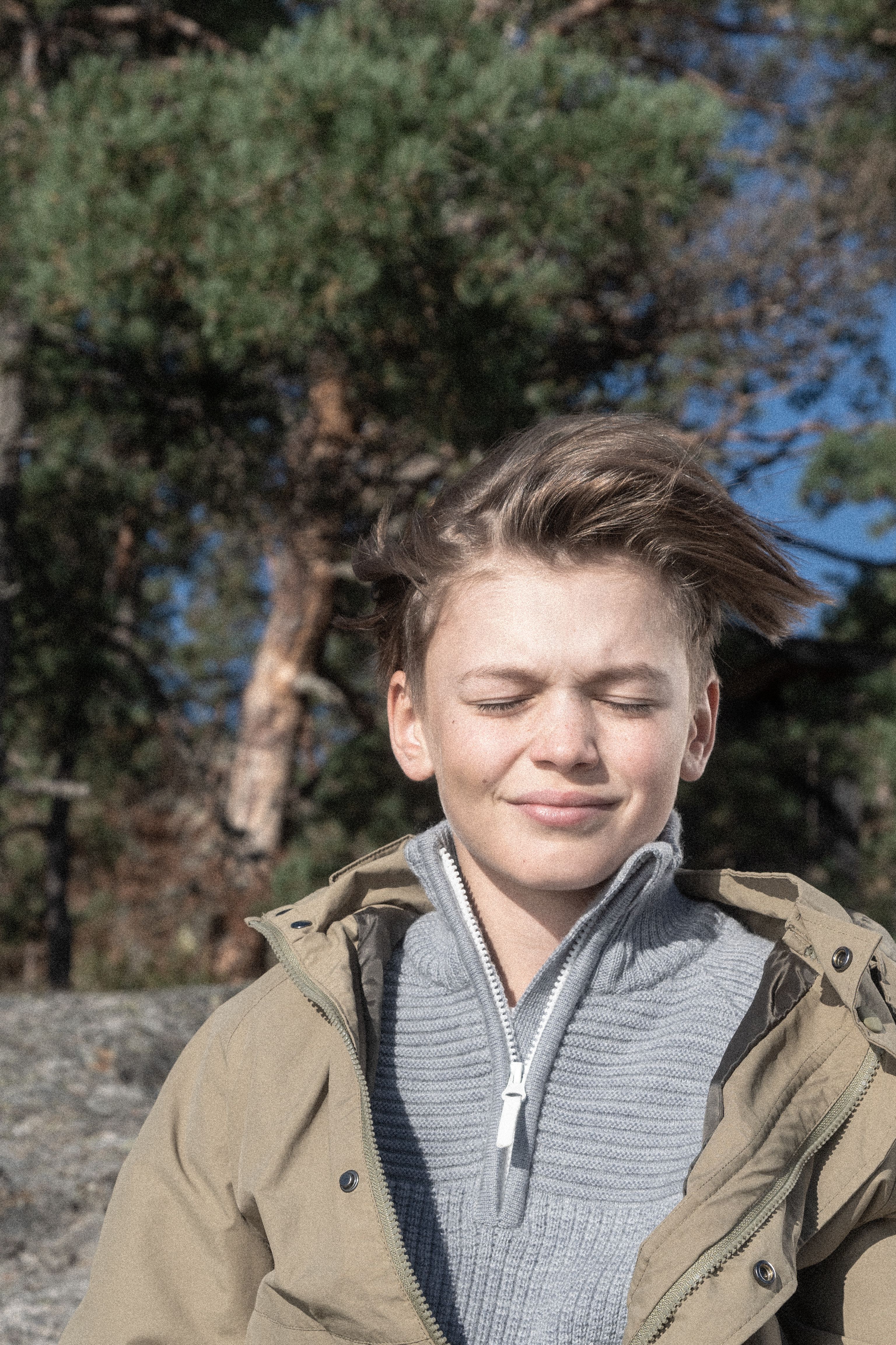 A boy enjoying the sun with his eyes closed.