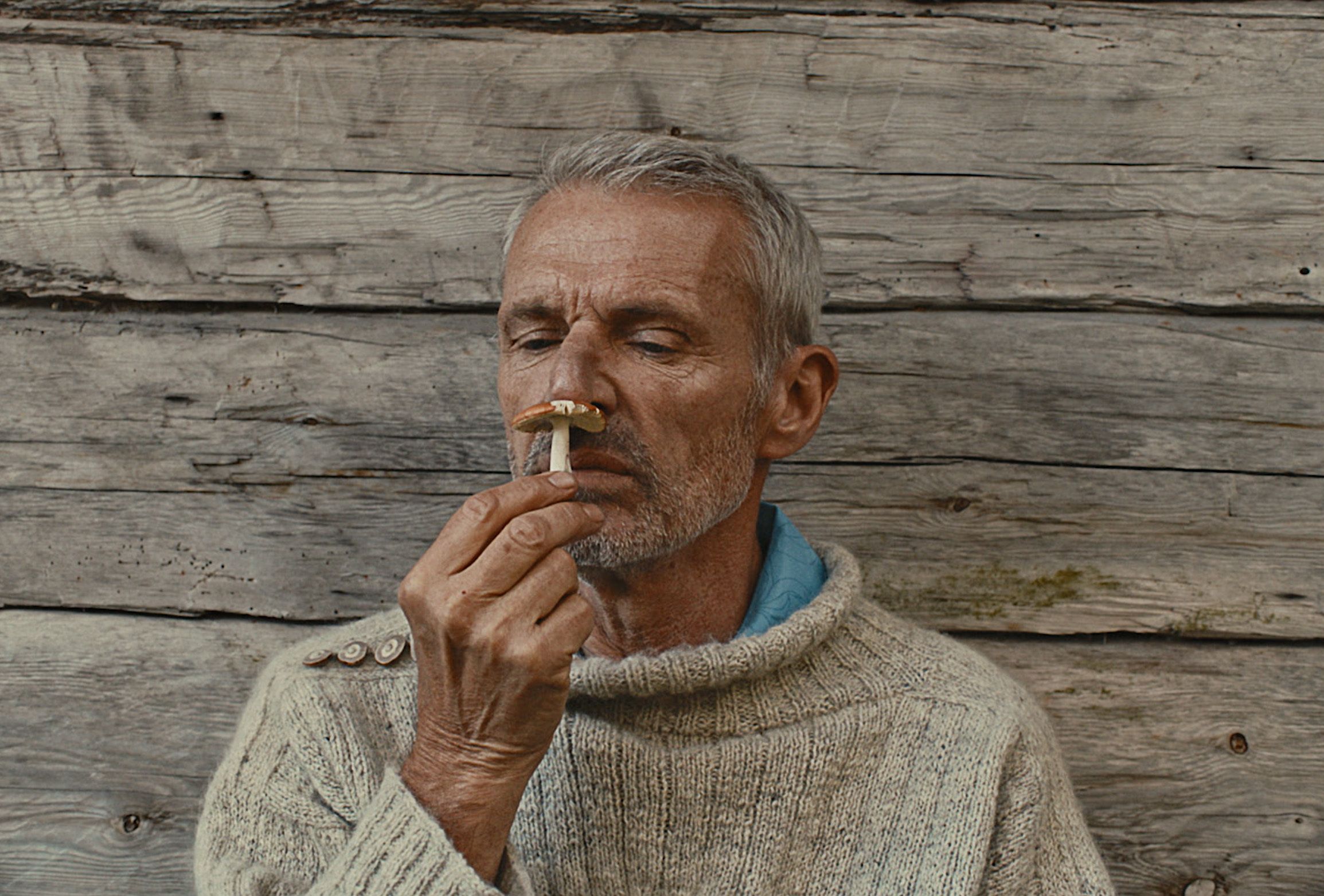 Lambert Wilson smelling a mushroom.