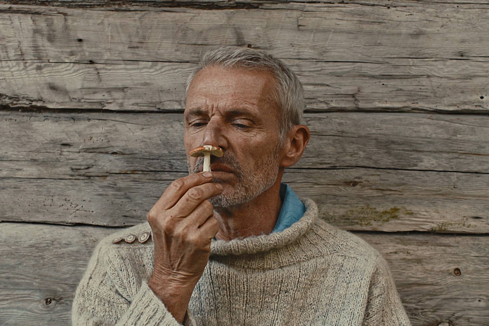 Lambert Wilson smelling a mushroom.