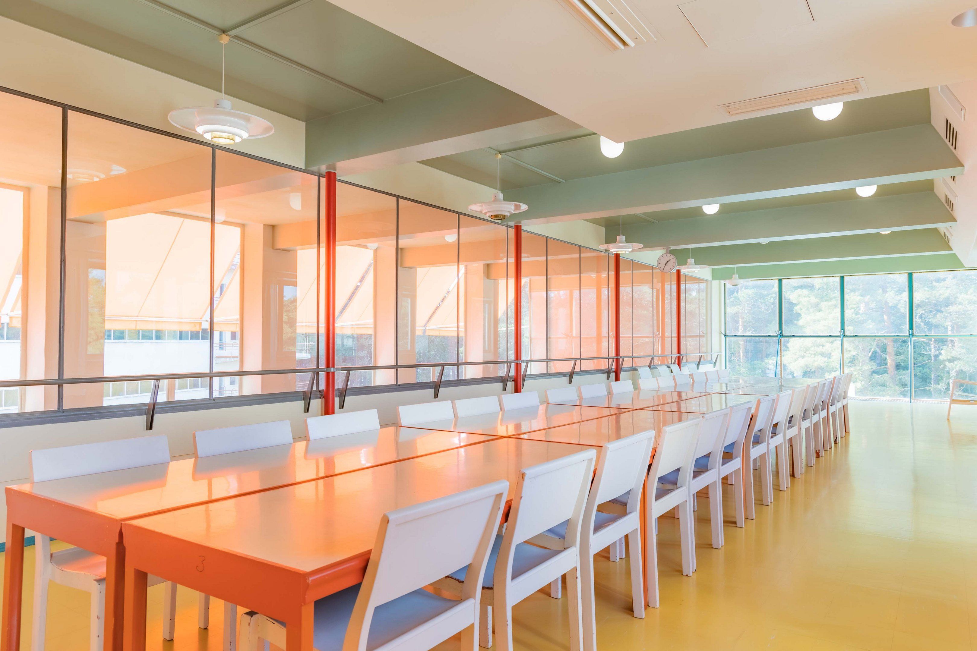 A colorful hall with tables and chairs in Paimio Sanatorium