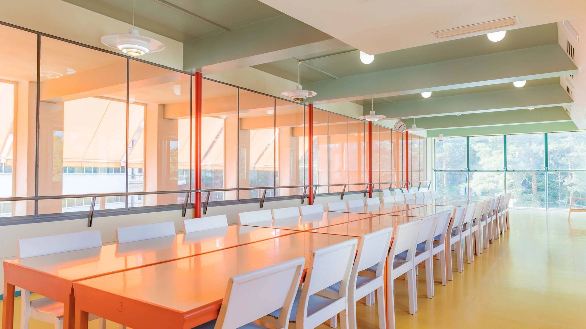 A colorful hall with tables and chairs in Paimio Sanatorium