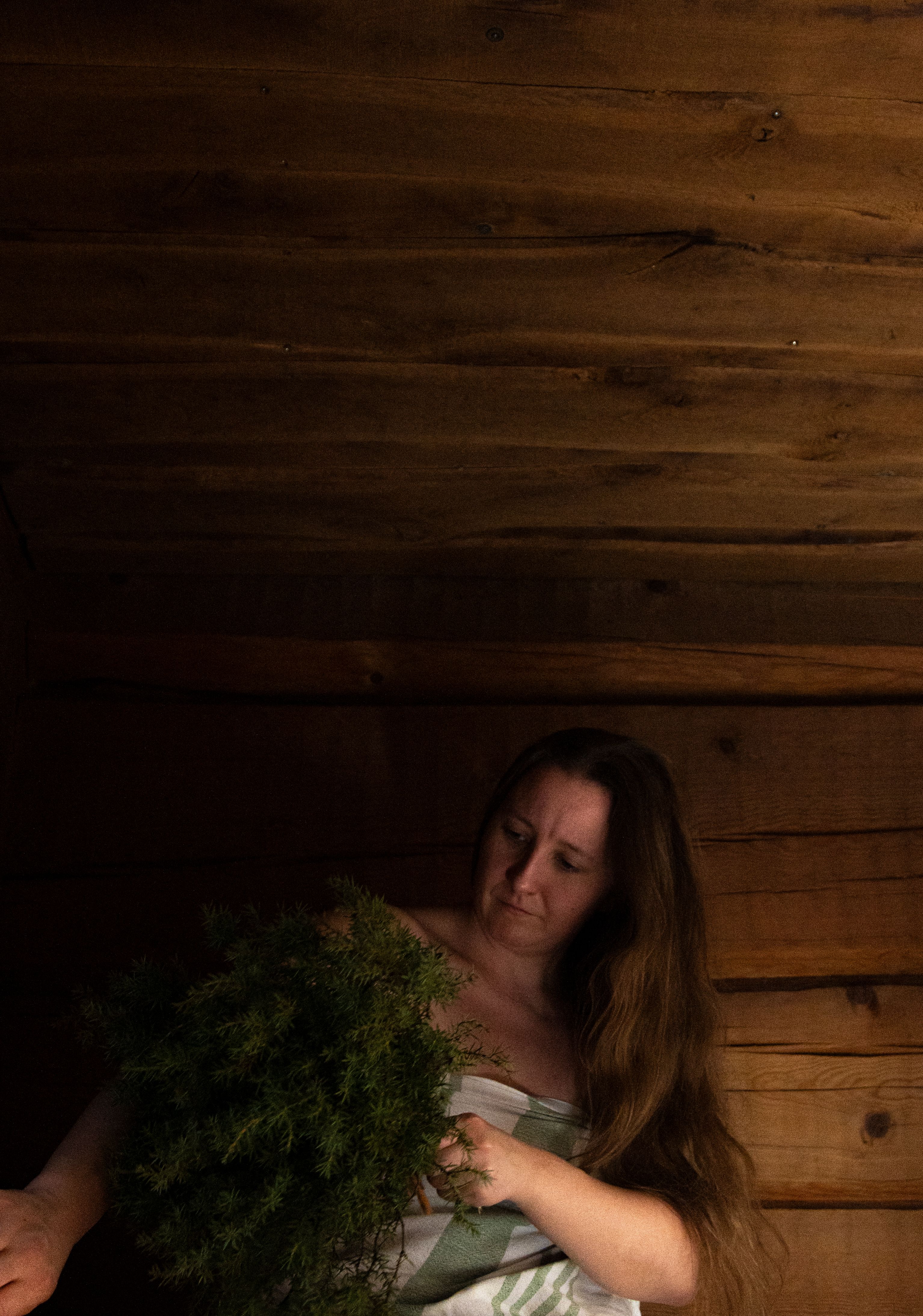 A woman whisking her skin with a tree branch.