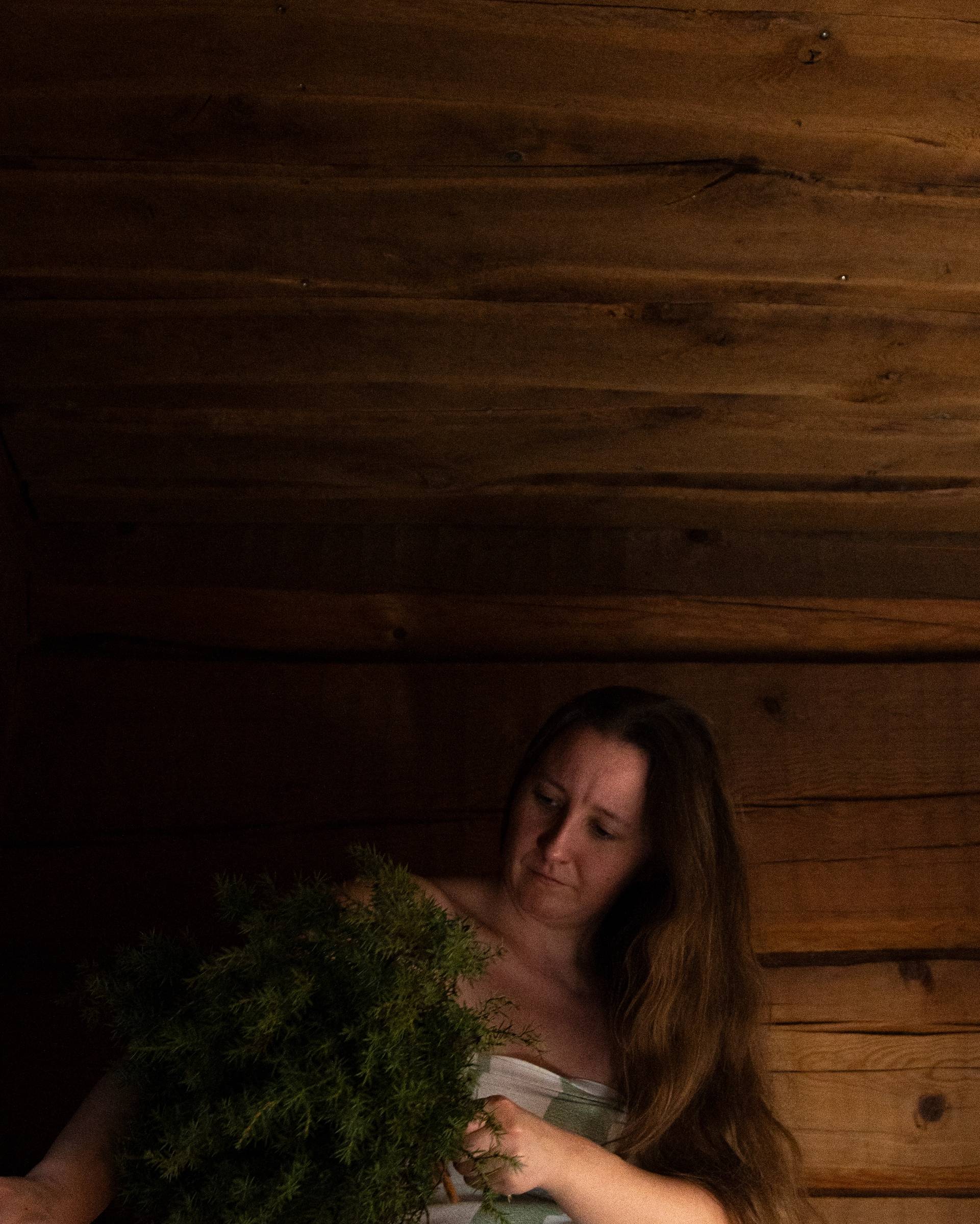 A woman whisking her skin with a tree branch.