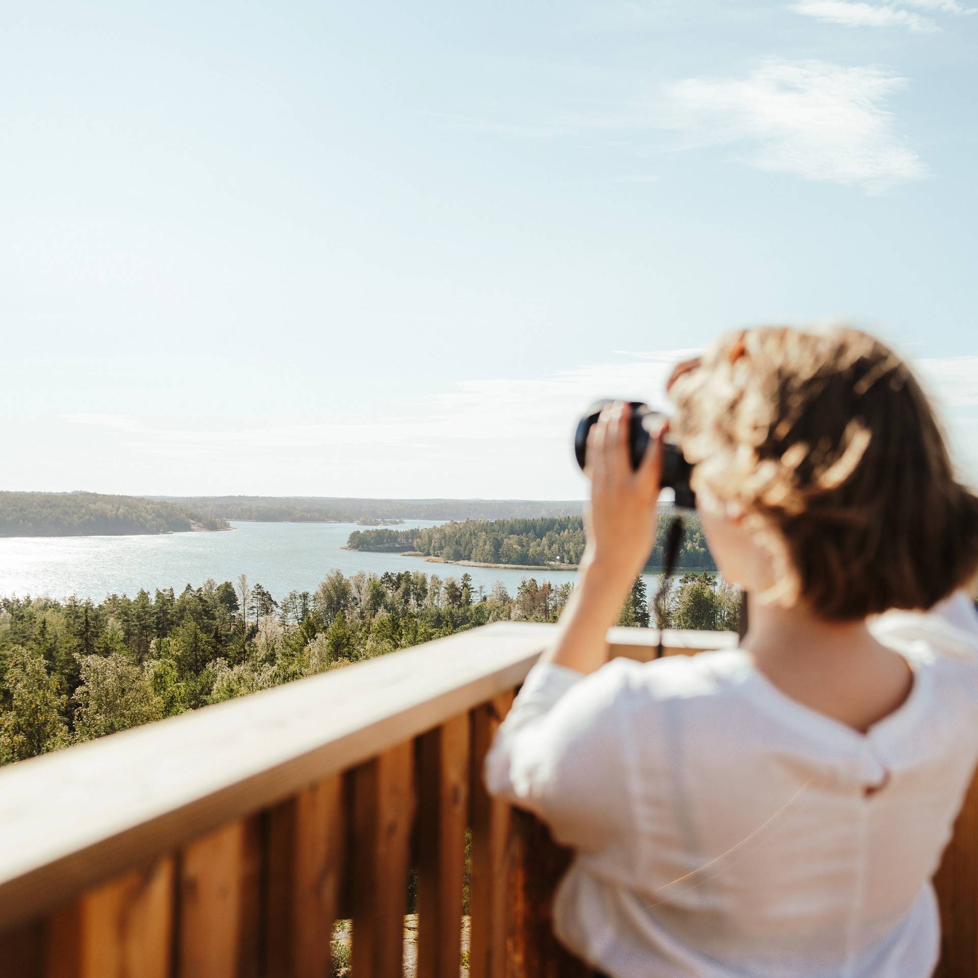 A woman looking at the archipelago through binoculars.