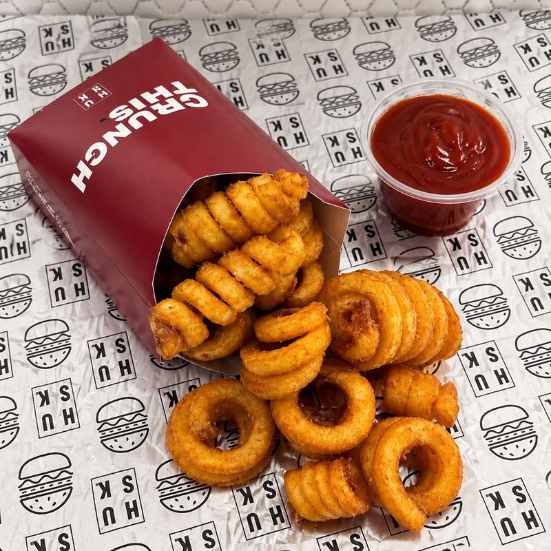 Twister fries spilling out of a red Husk box, with a cup of ketchup