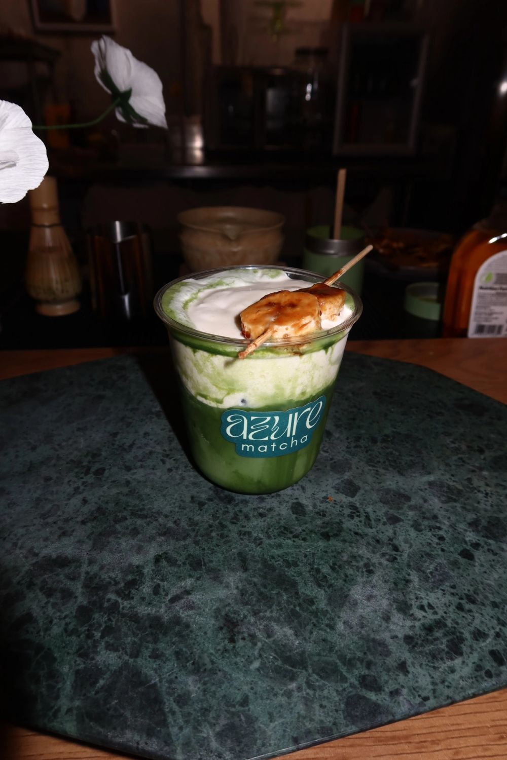 Iced matcha latte with cream foam and a brûléed banana skewer, Azure Matcha