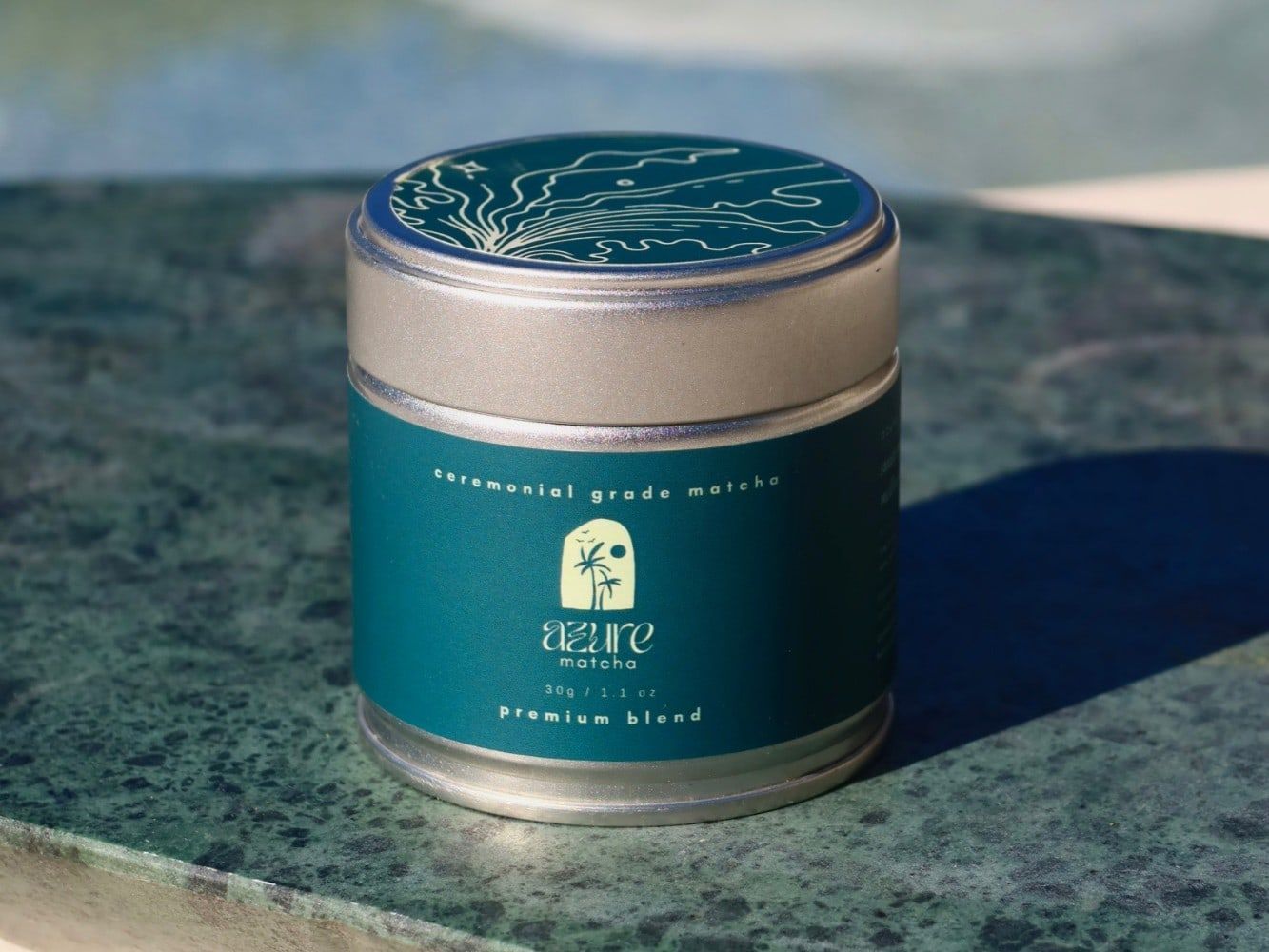 The Azure Matcha Premium Blend 30g tin on green marble by the pool