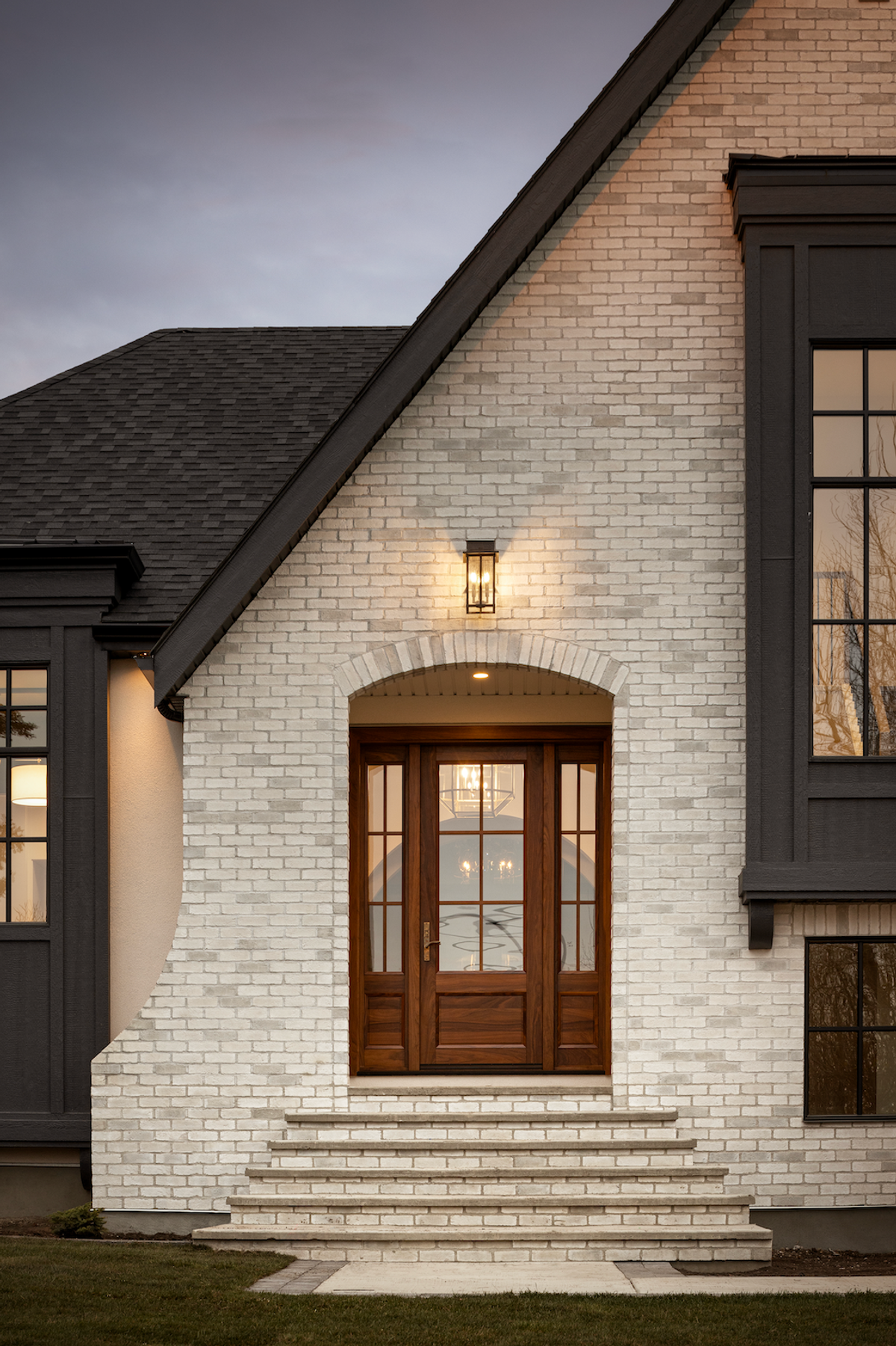 White brick entry with wood door at dusk