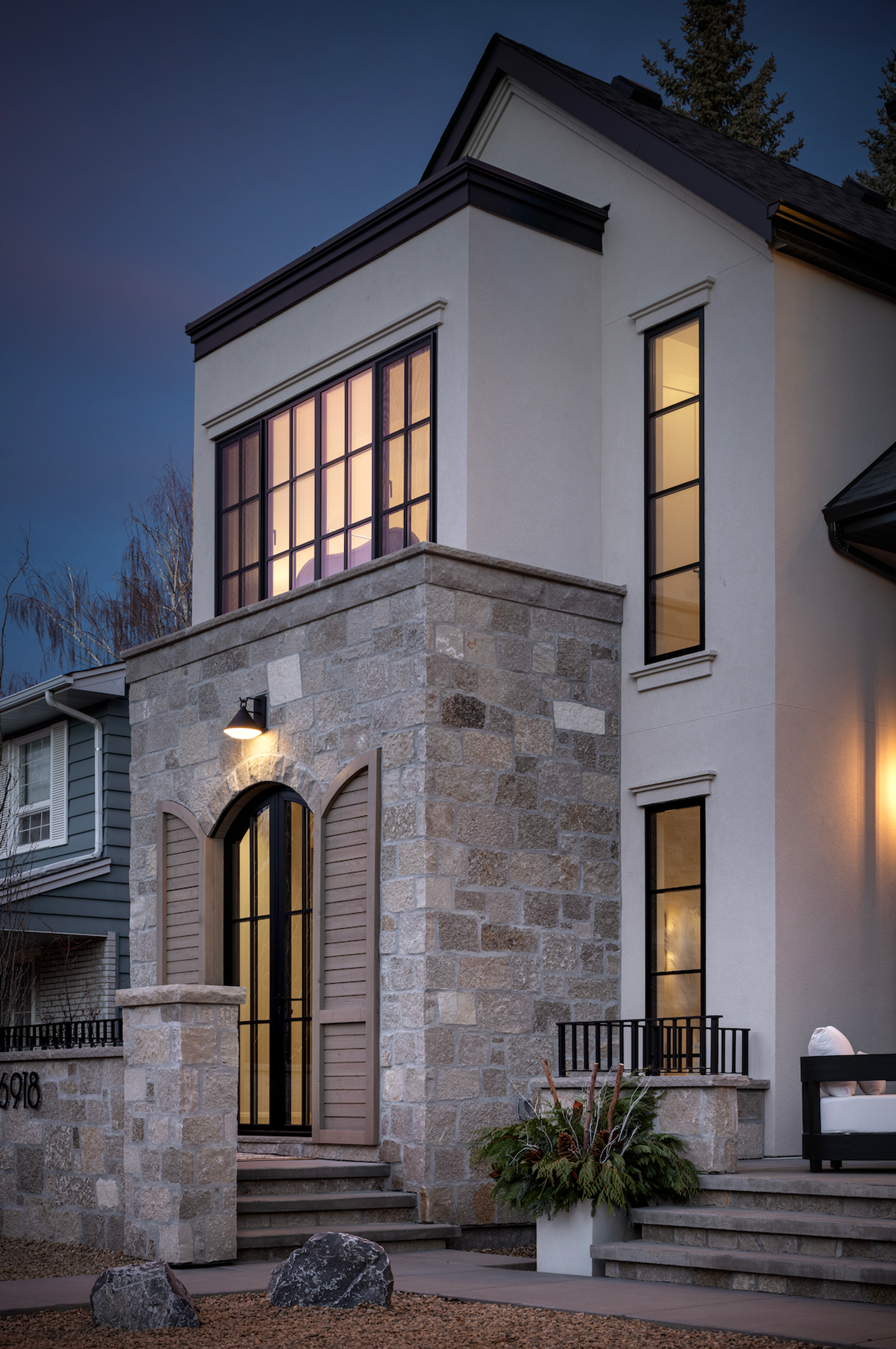 Front exterior of a stone and stucco home at dusk