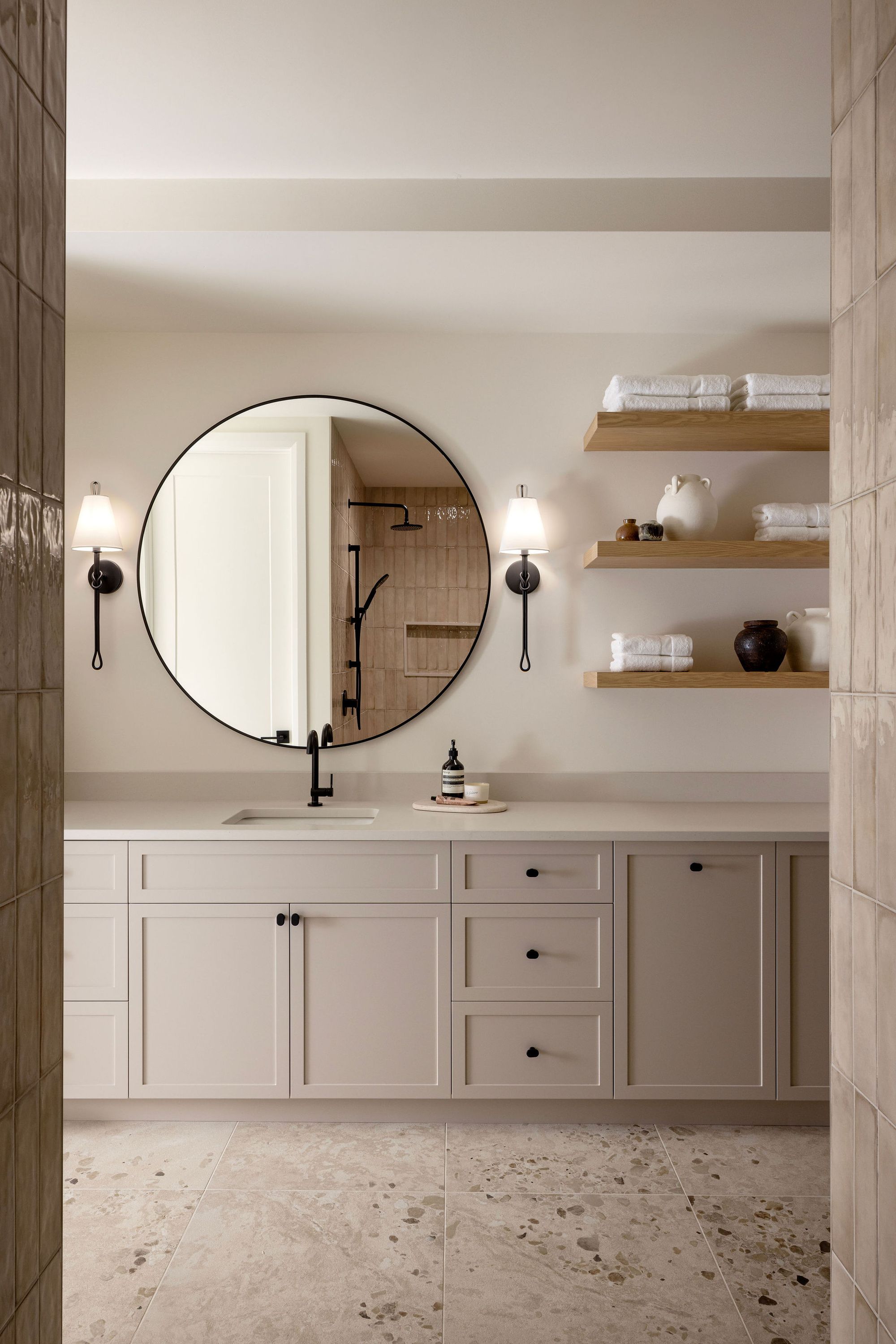 Bathroom with round mirror and open shelves in The Charlotte home