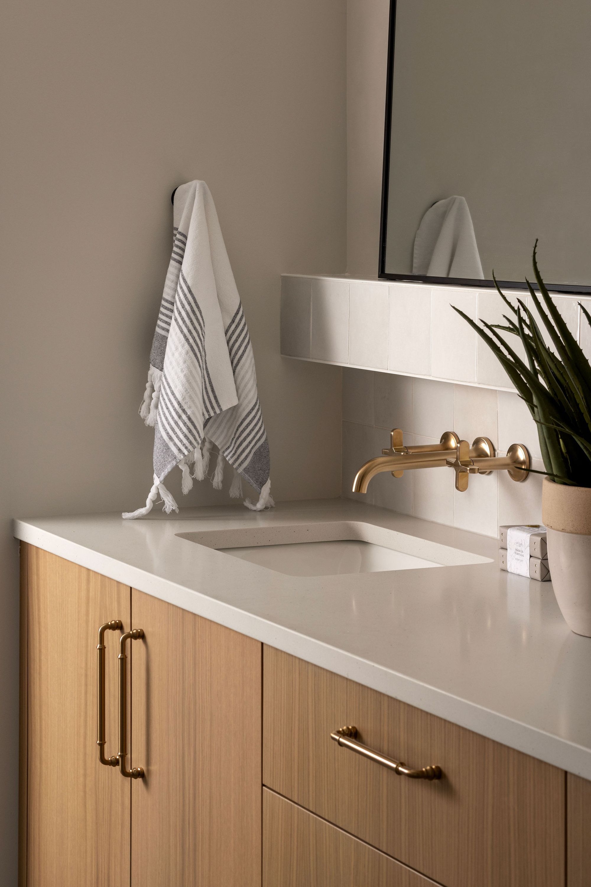Bathroom vanity with a brass wall faucet in the Priddis home