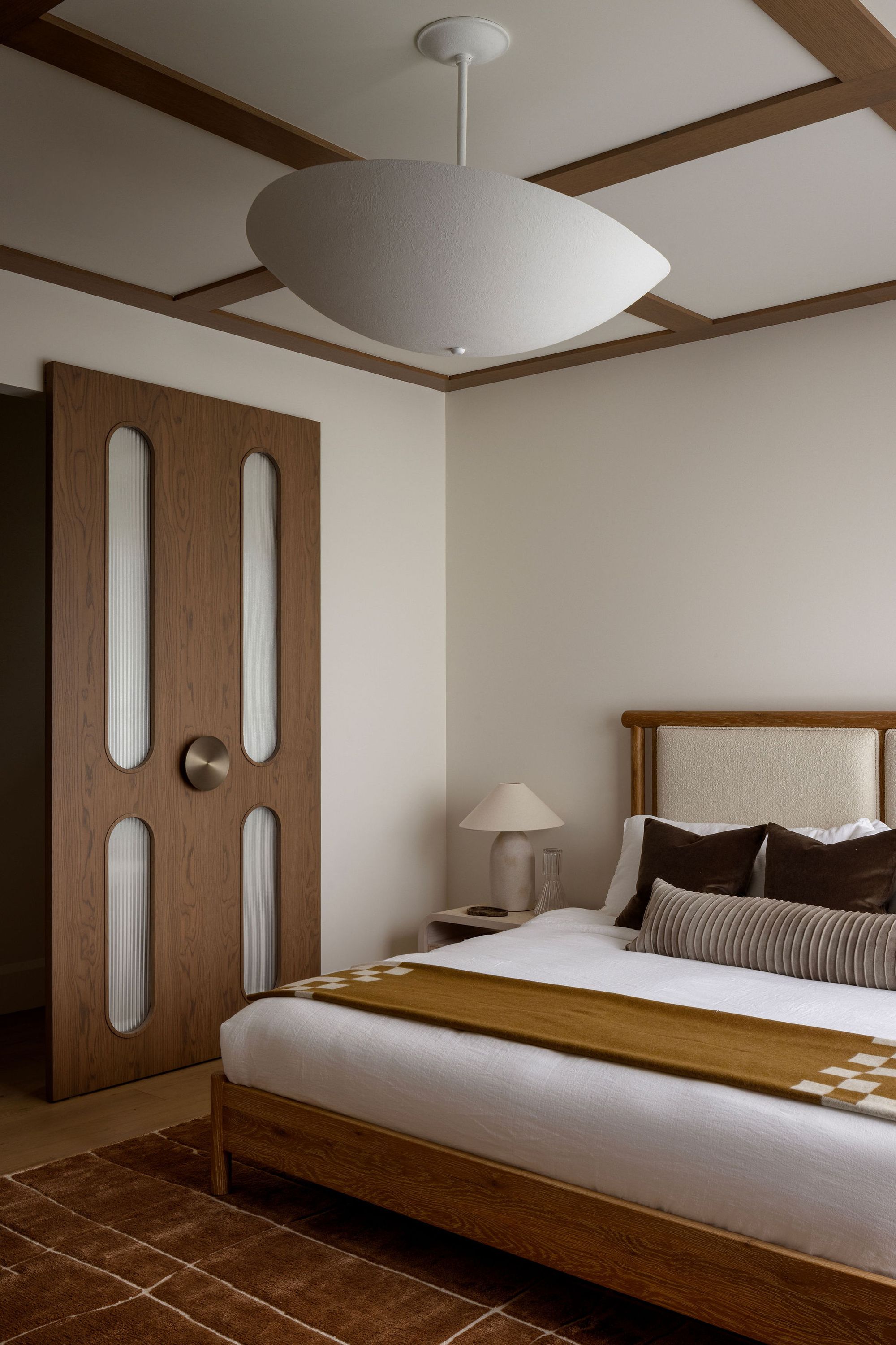 Bedroom with wood door and exposed ceiling beams in The Charlotte home